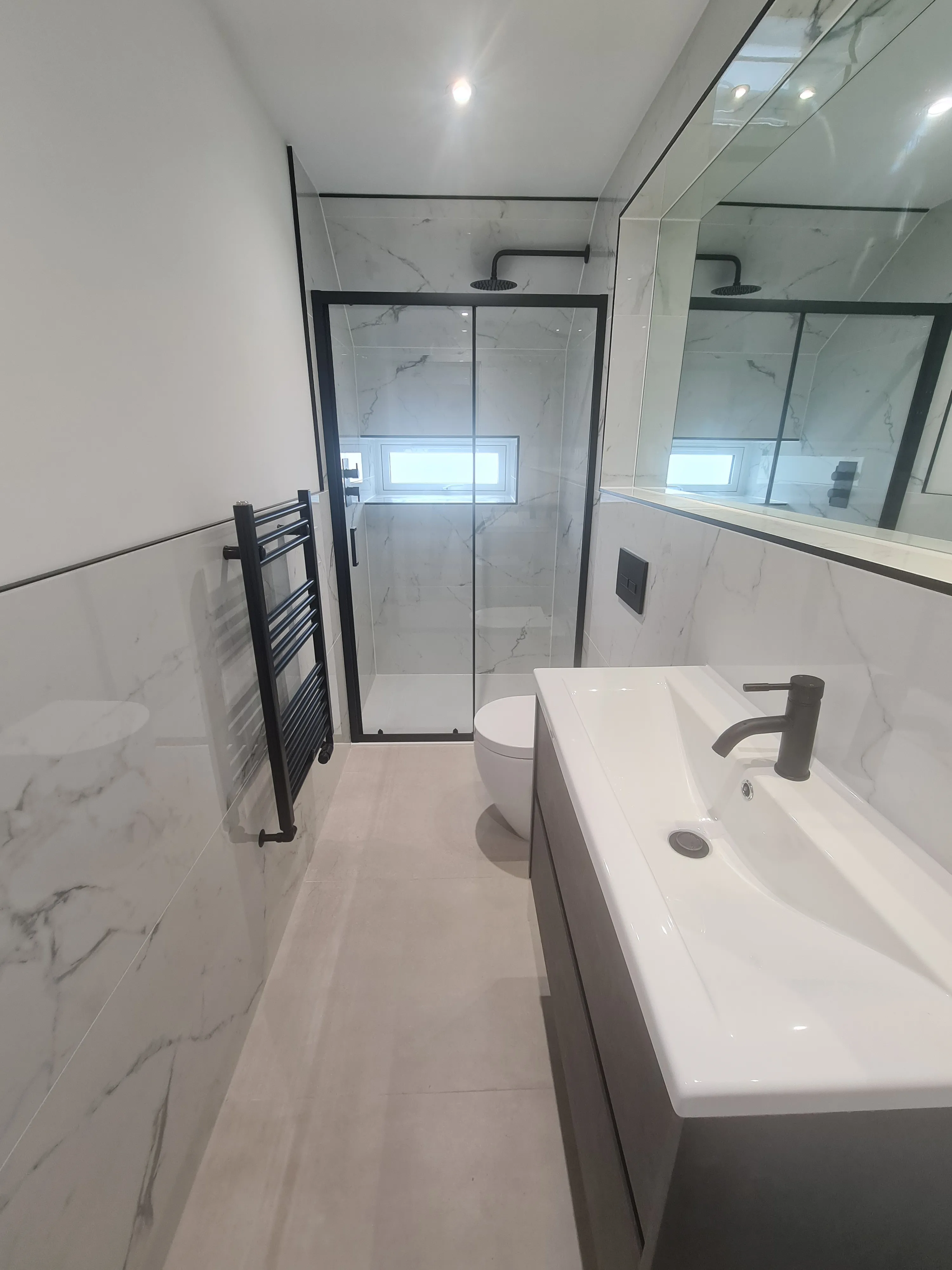 Bespoke luxury walk-in shower installation in Plymouth featuring marble tiles and black accents by Sands & Vossen