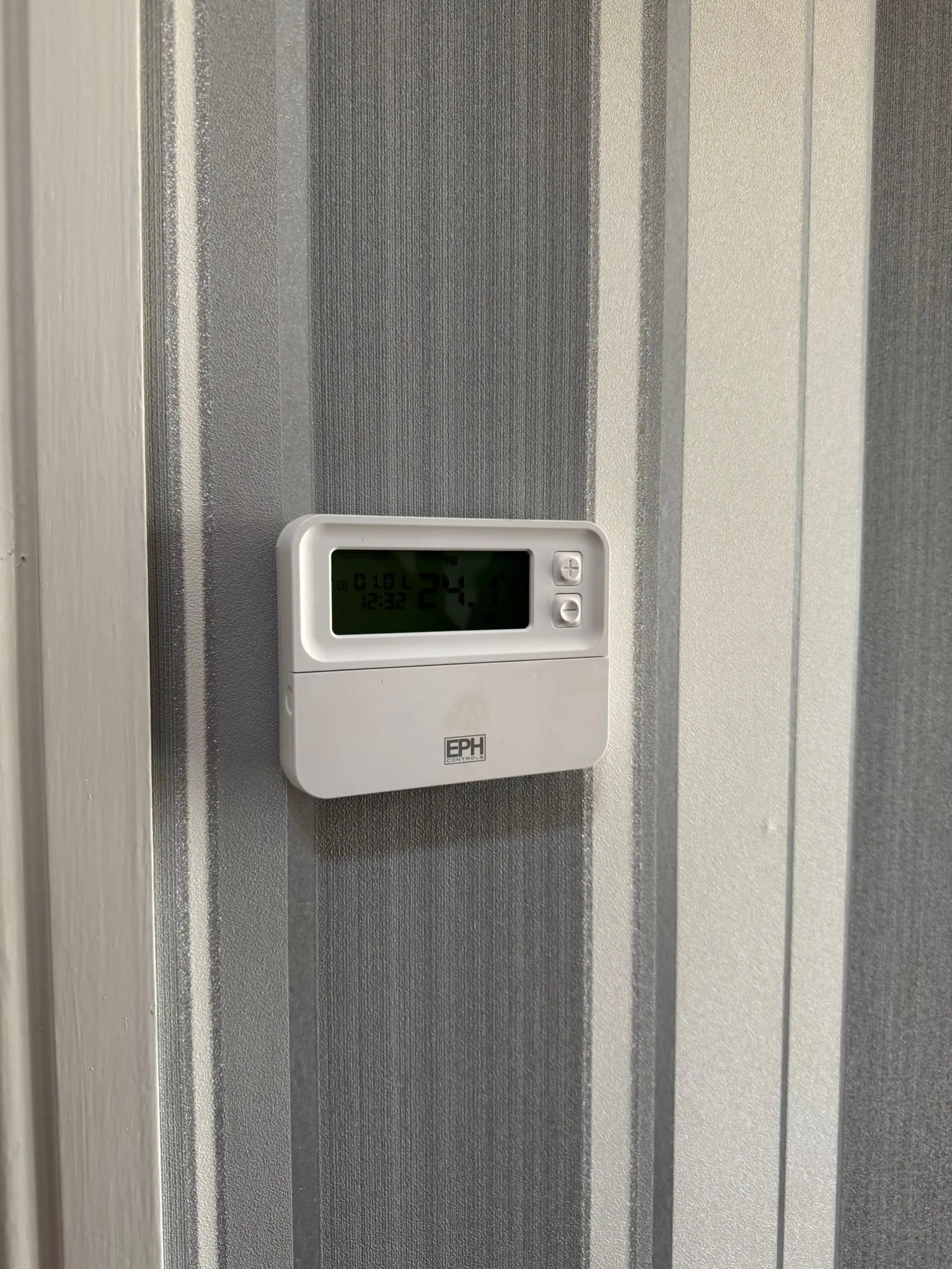 An EPH Controls digital central heating thermostat on a wall.