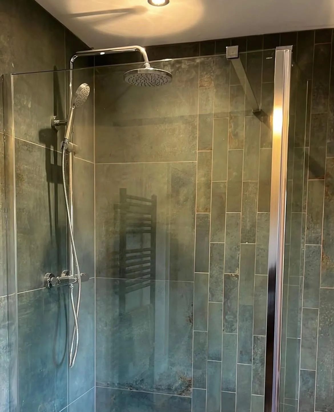 Modern walk-in shower installation with rainfall showerhead and dark tiles in a York bathroom.