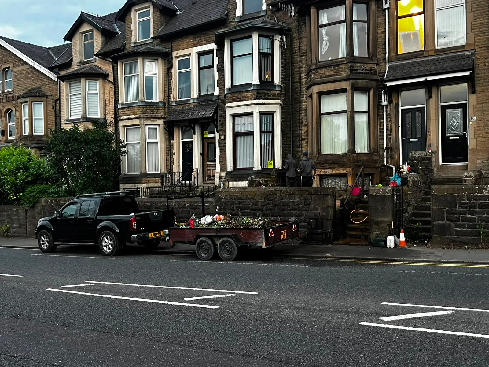 Maintenance truck and trailer parked outside stone terraced houses in Burnley.