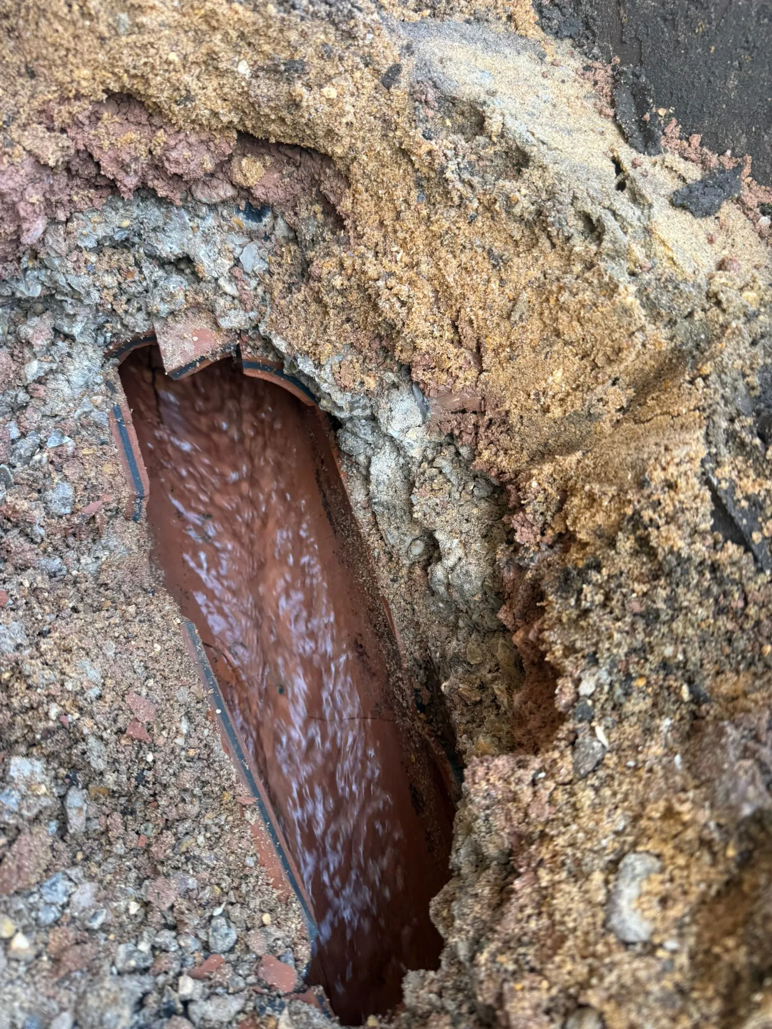 Excavated clay drainage pipe with water flowing through it