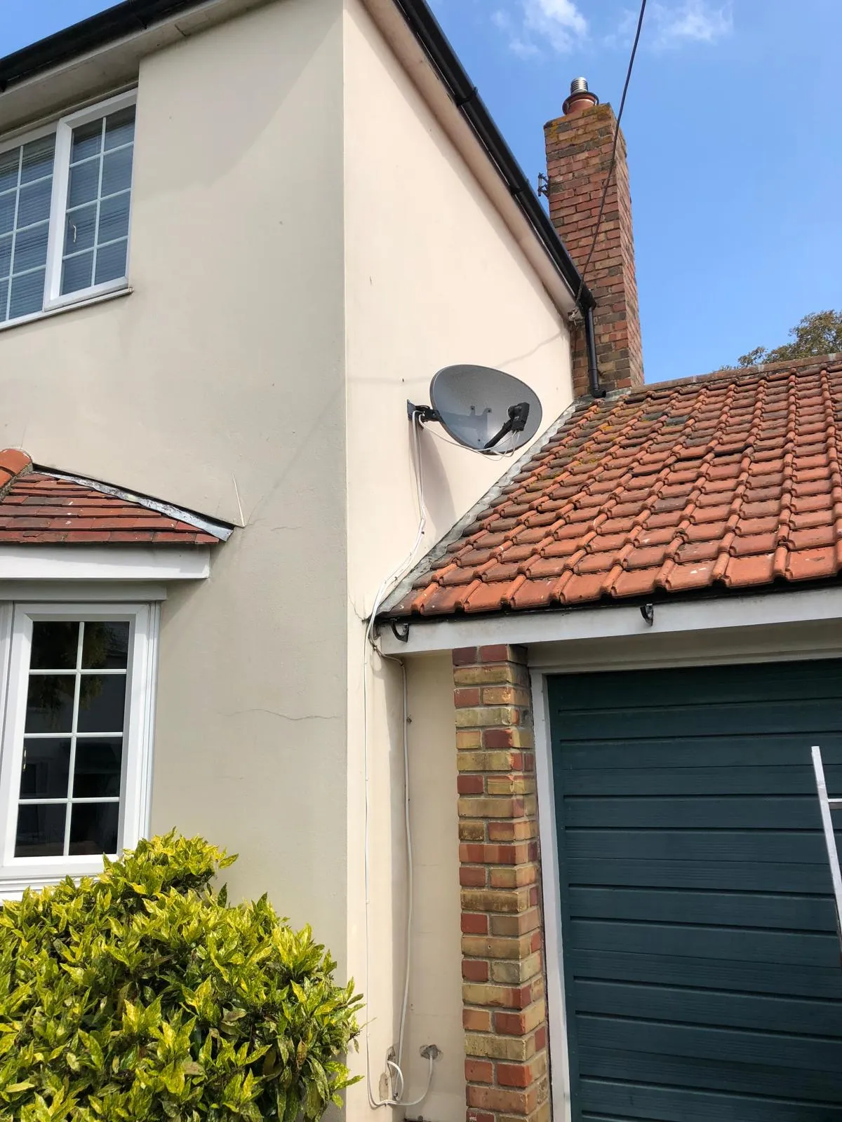 Exterior of a house with a tiled roof, rendered walls, uPVC windows, fascias, and a green garage.