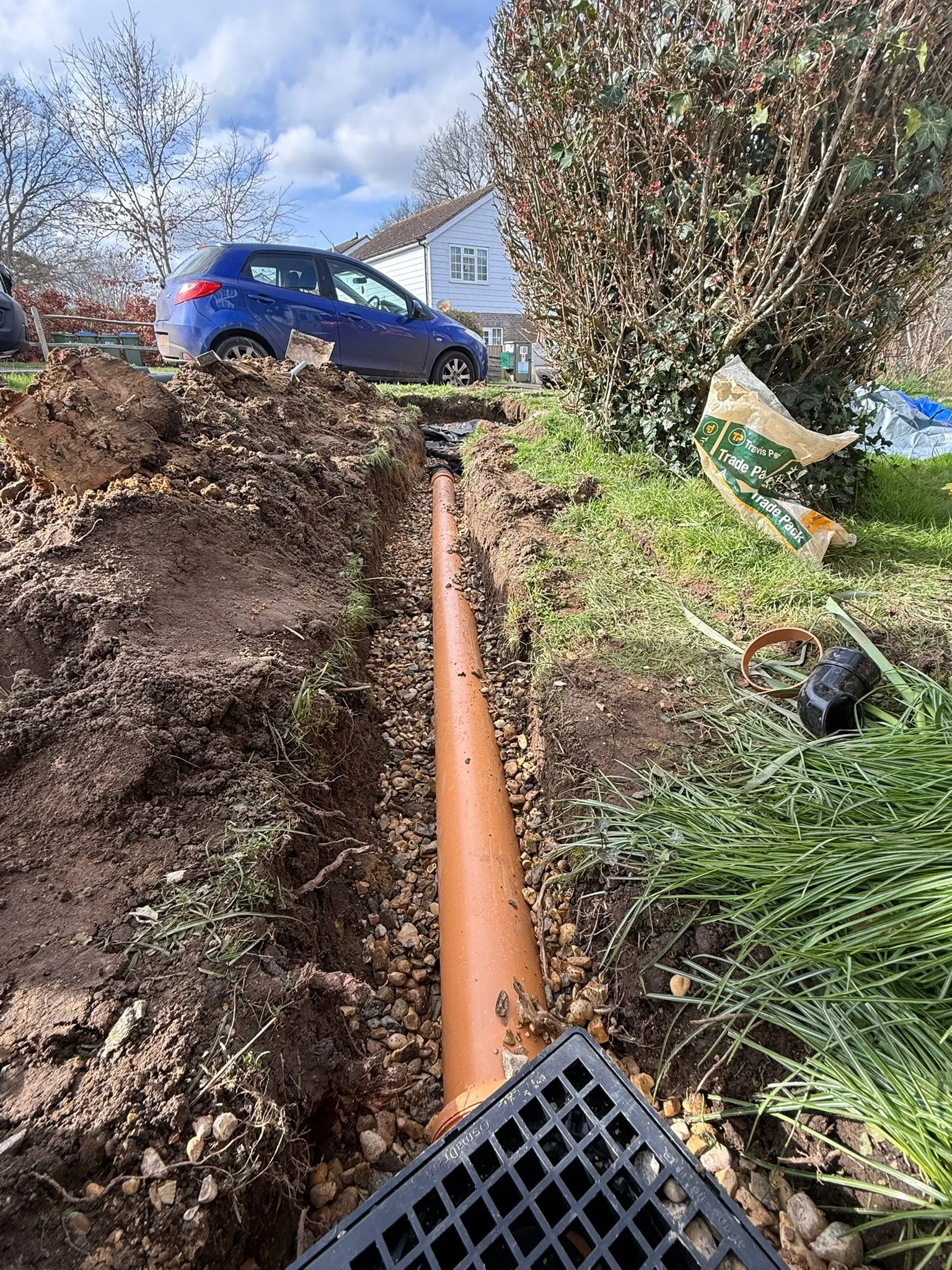 New underground drainage pipe installation in a garden trench.