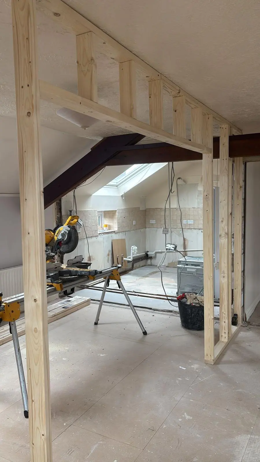 A Fortura Construction LTD plasterer mixing materials in a yellow bucket during a premium home renovation in the Cotswolds, with freshly skimmed walls visible in the background.