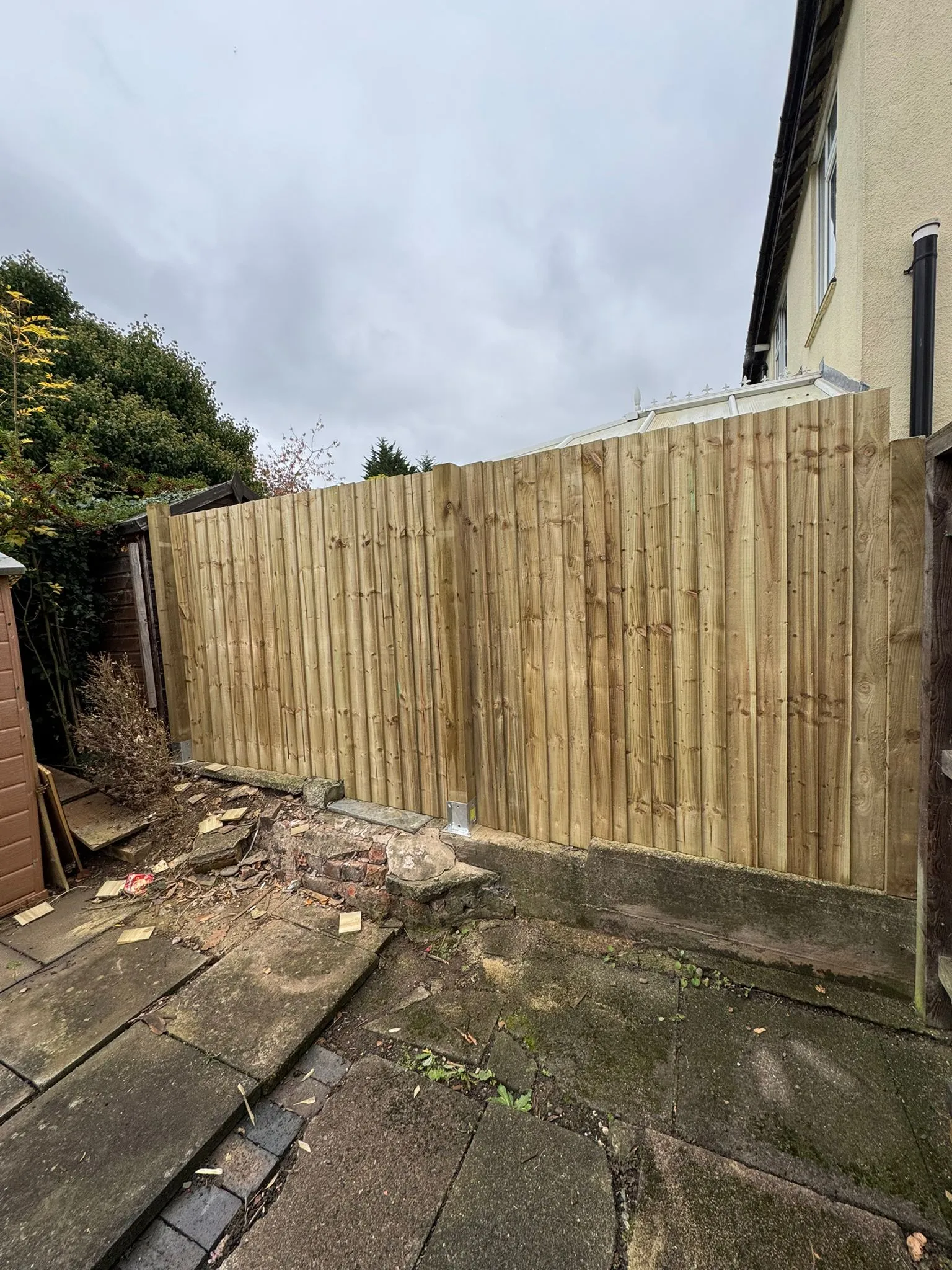 Newly installed timber closeboard fence with ground preparation visible in a garden.