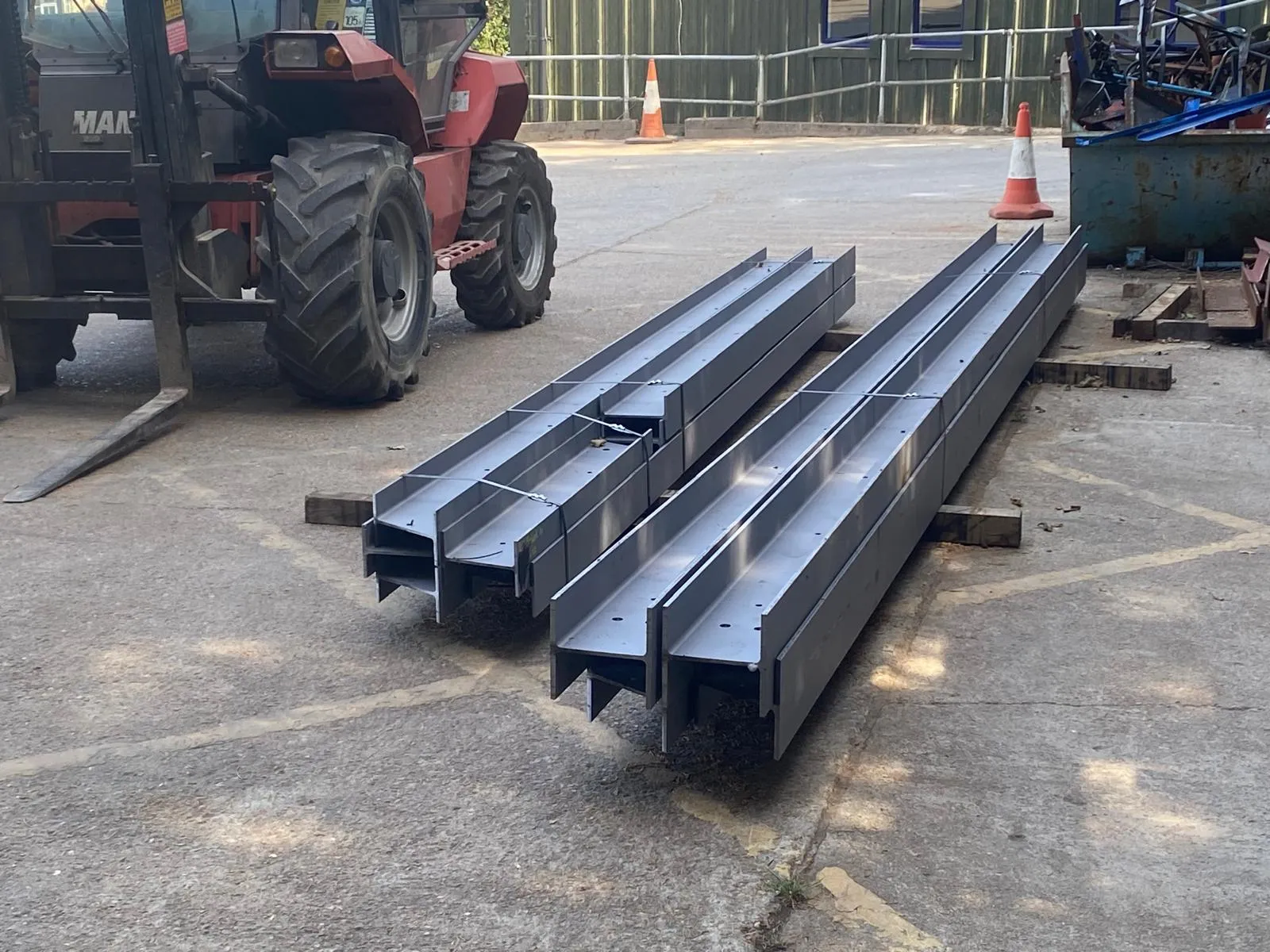 A collection of grey structural steel beams and RSJs fabricated for a construction project.