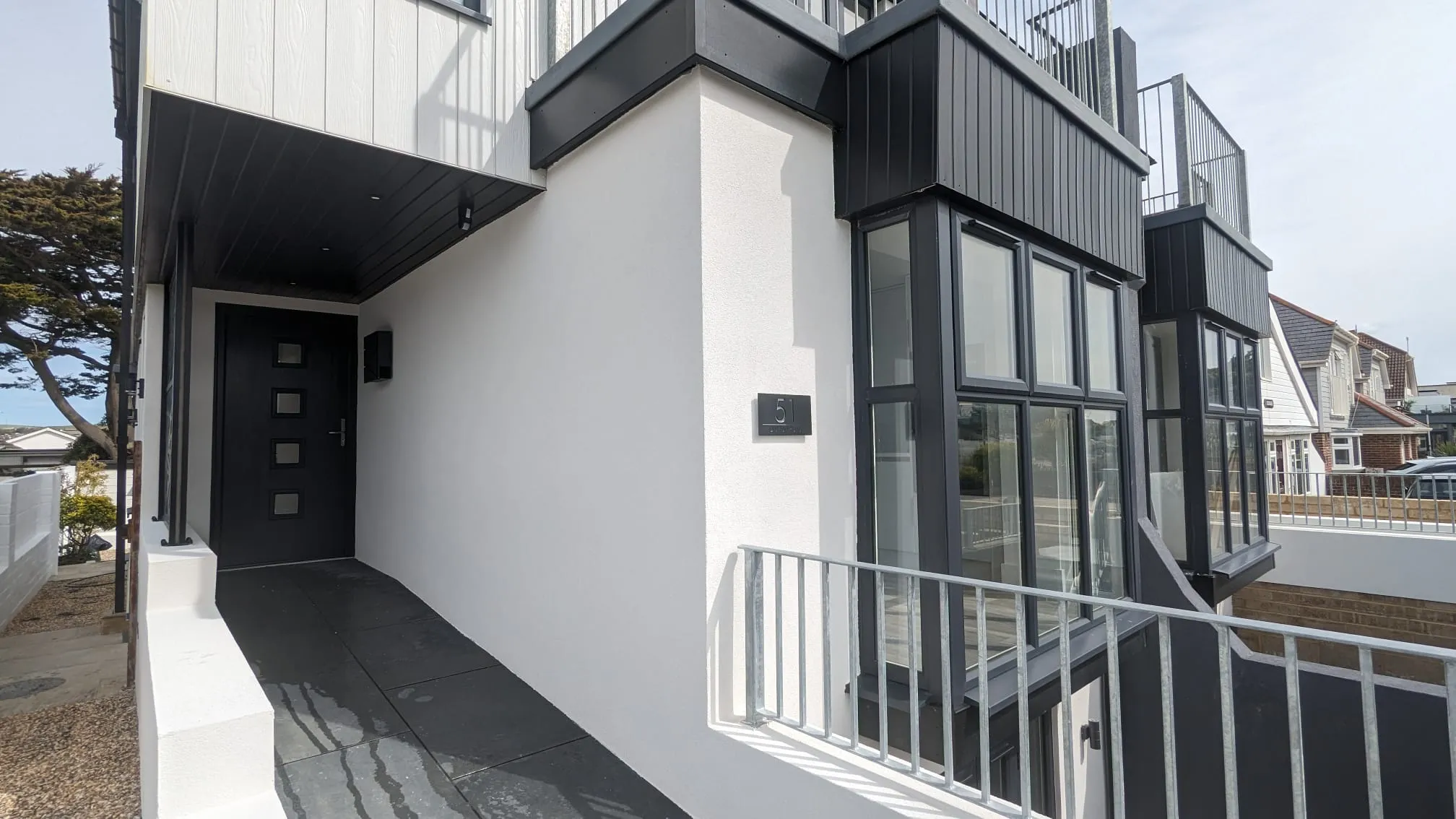 Modern house exterior with professional white rendering and black architectural details.