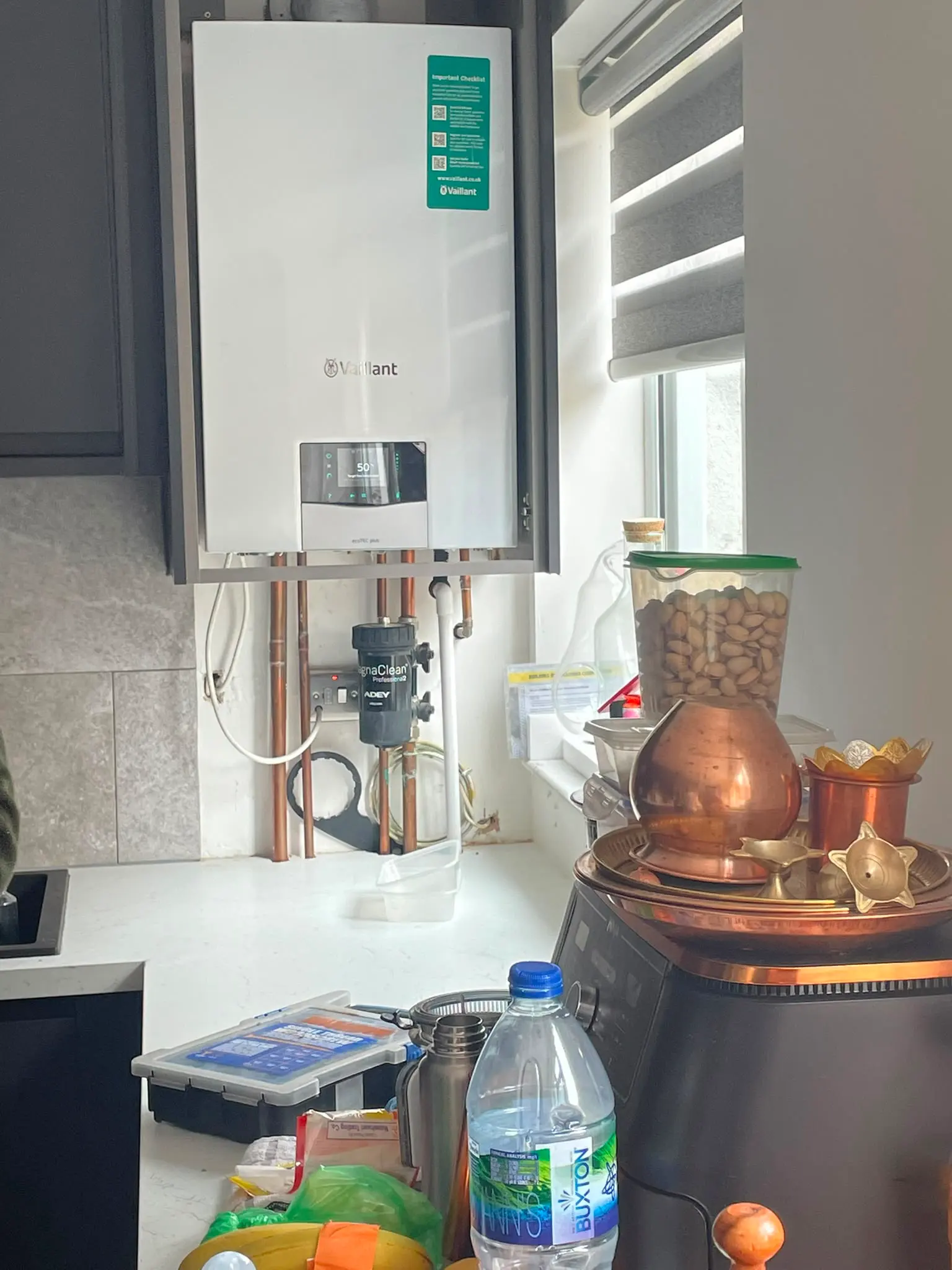 Newly installed copper pipework and MagnaClean filter beneath a wall-mounted boiler in a kitchen