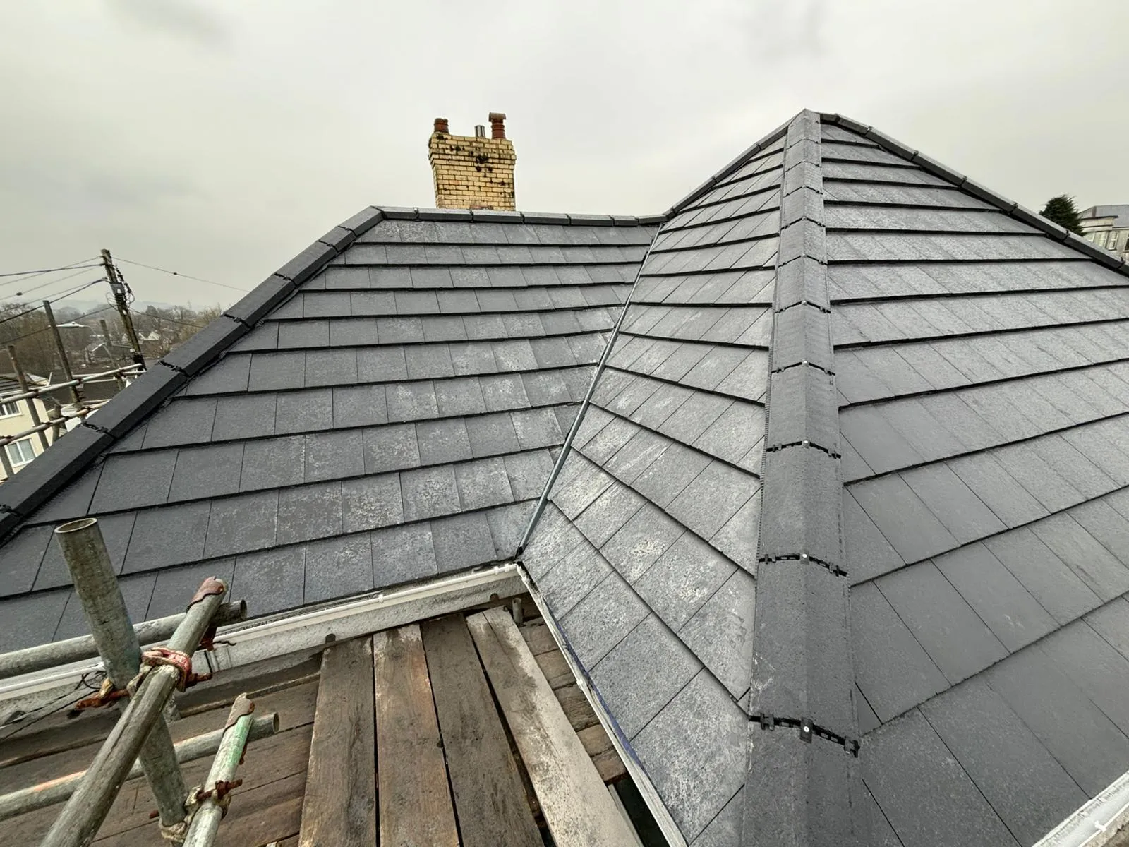 Professional pitched roof installation with dark grey tiles and dry ridge system.