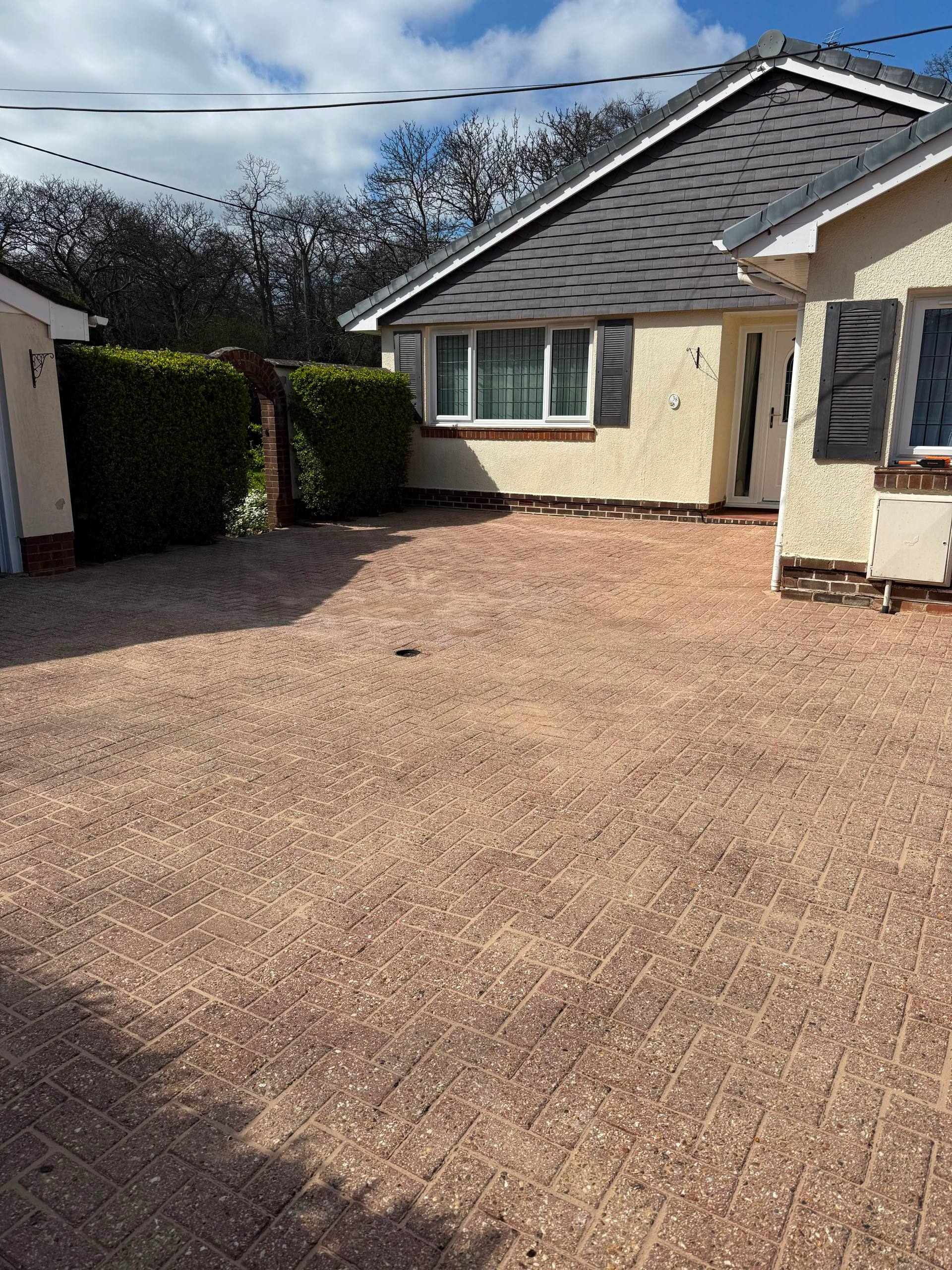 A pristine, professionally cleaned block paved driveway in front of a residential home.