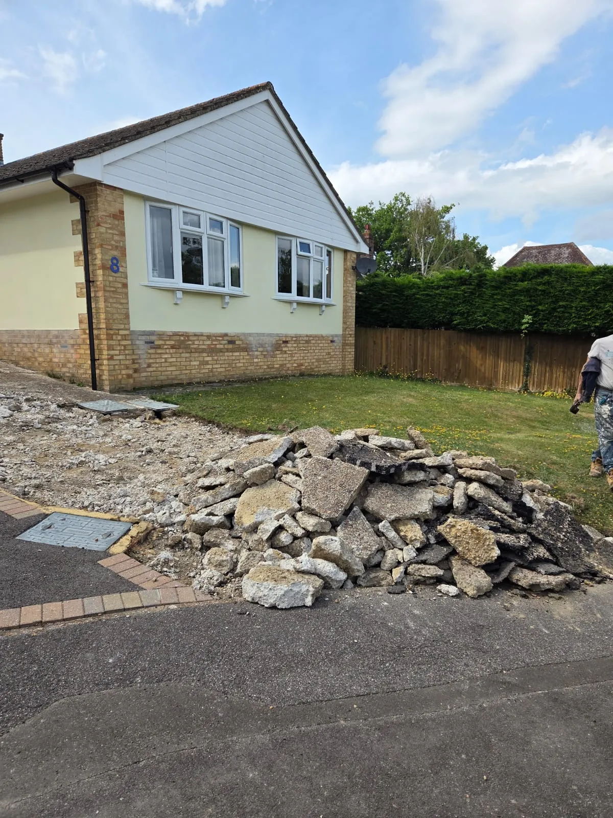 Driveway excavation and groundworks in progress at a residential property, showing a pile of rubble and broken concrete being cleared for a new surface.