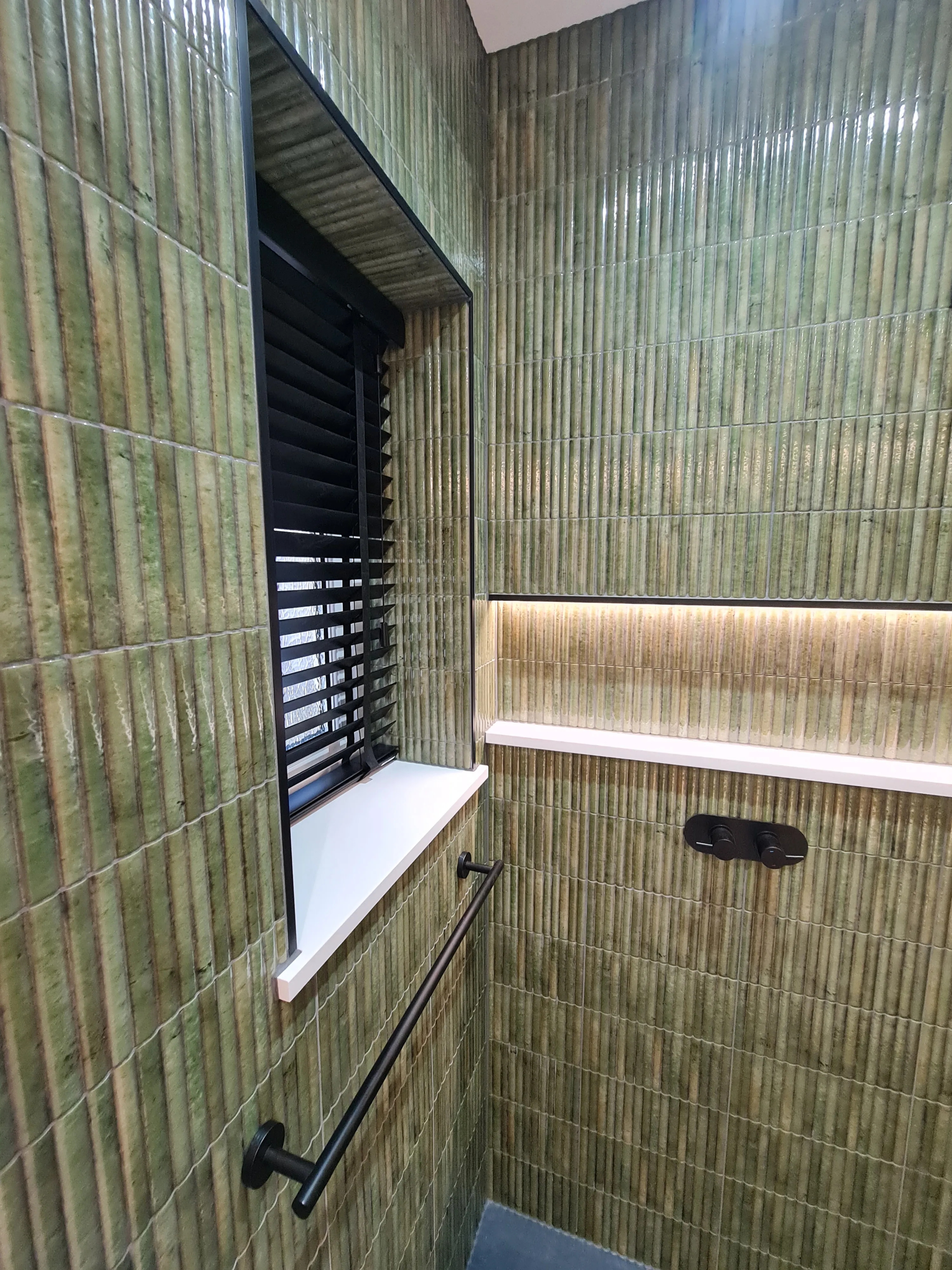 Bespoke luxury walk-in shower with green fluted tiles and integrated lighting in a Plymouth home by Sands & Vossen.