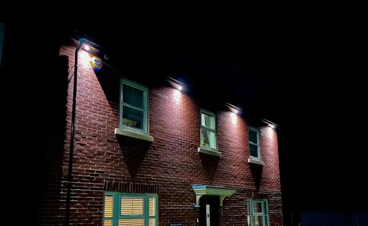 Outdoor soffit downlights and security lighting illuminating the brick facade of a home at night
