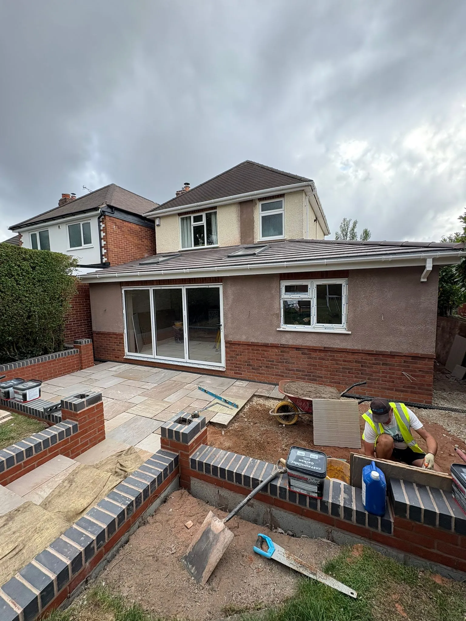 A nearly completed single-storey home extension with large bifold doors and a new patio.
