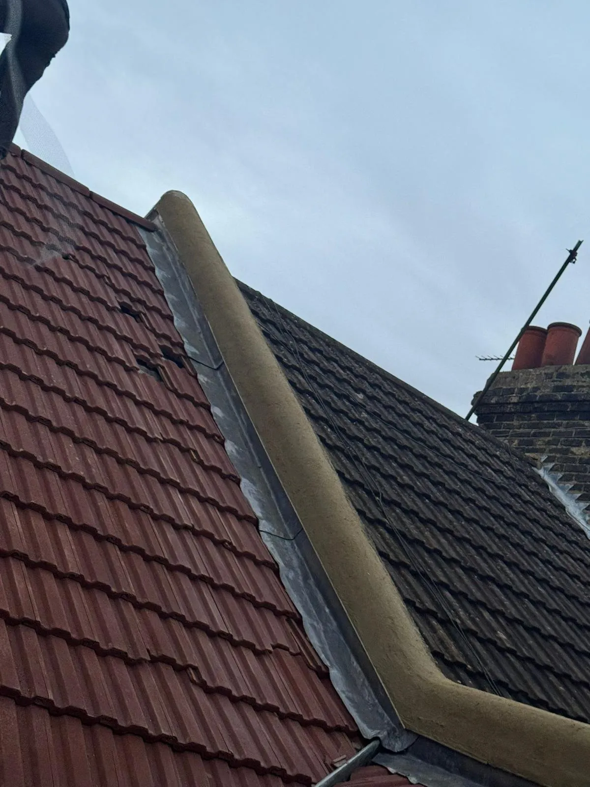 Lead flashing and roof tiles along a shared parapet party wall on a terraced house