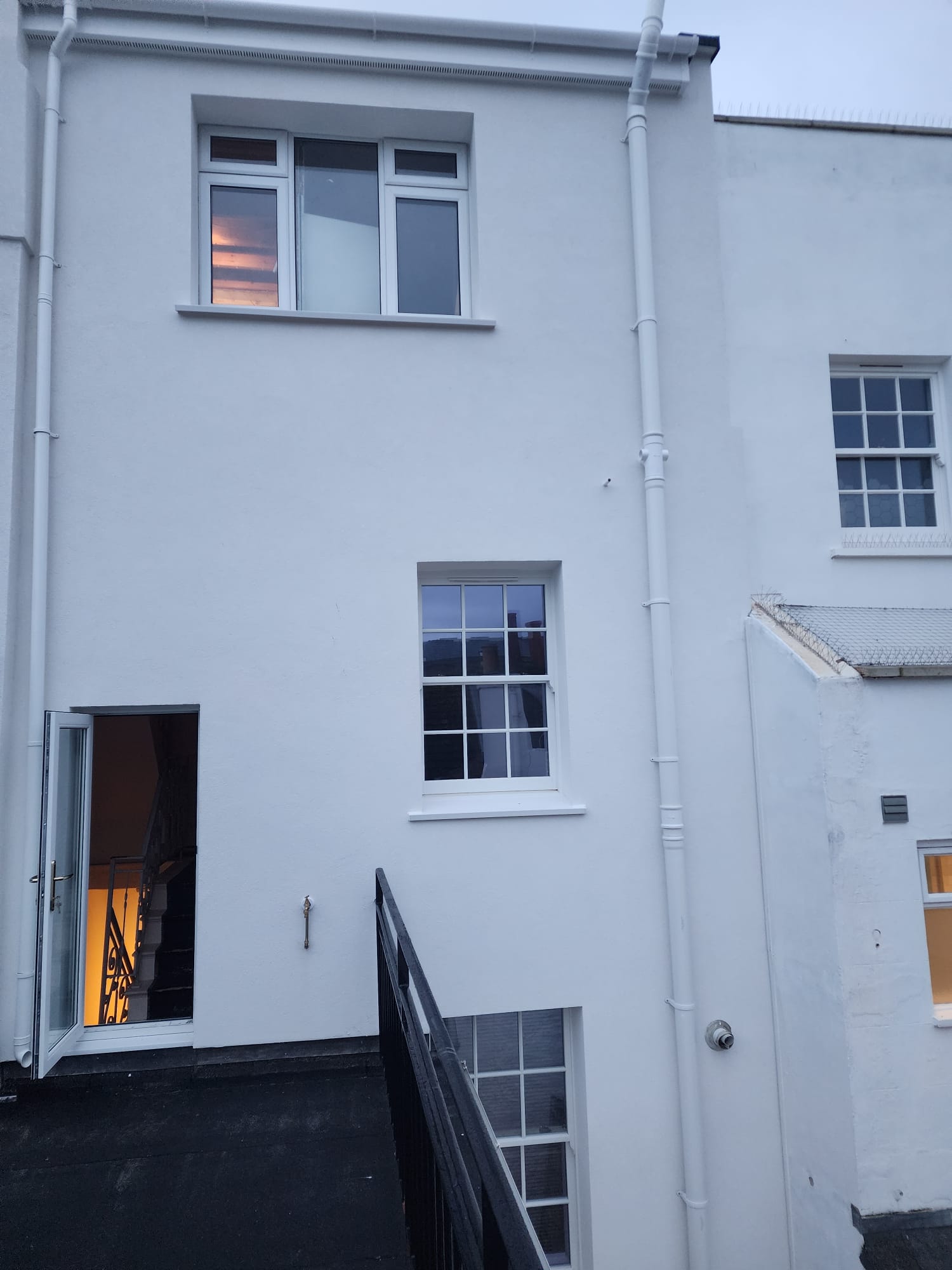 Freshly rendered white exterior wall on a residential property.