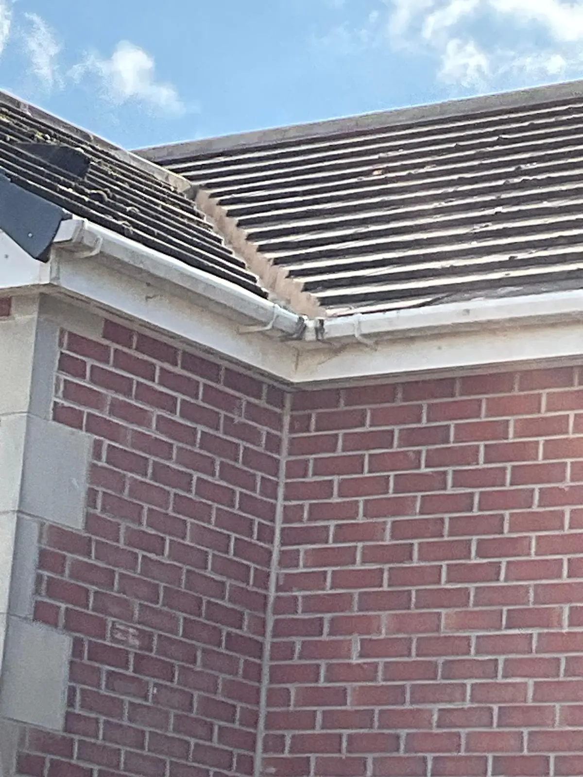 A close-up view of a tiled pitched roof showing the valley detail and uPVC roofline guttering on a brick residential property