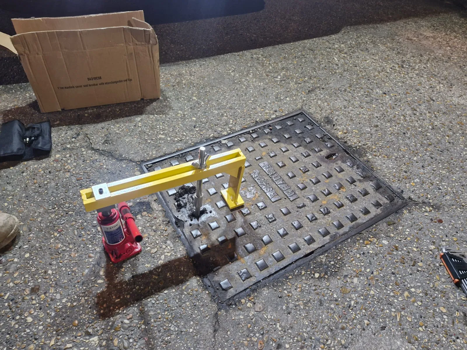 Hydraulic manhole cover lifter being used by Roberts Drainage Ltd to access underground pipes.