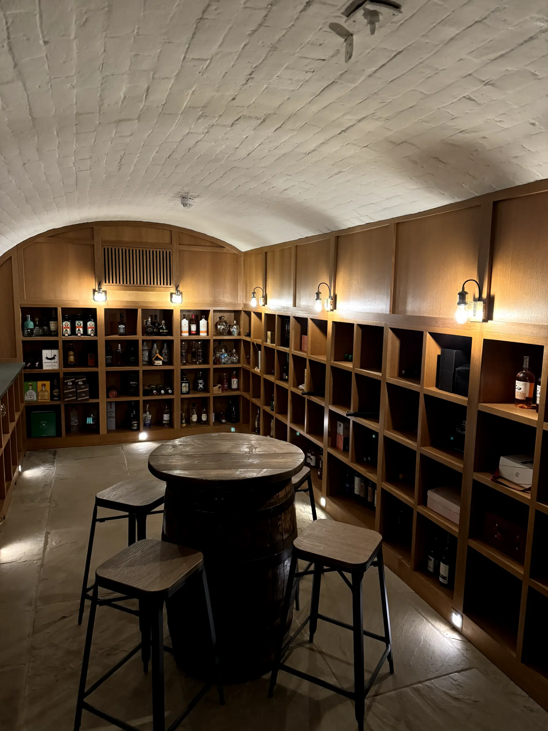 A custom wood-panelled wine cellar featuring bespoke wall sconce lighting and low-level floor LEDs