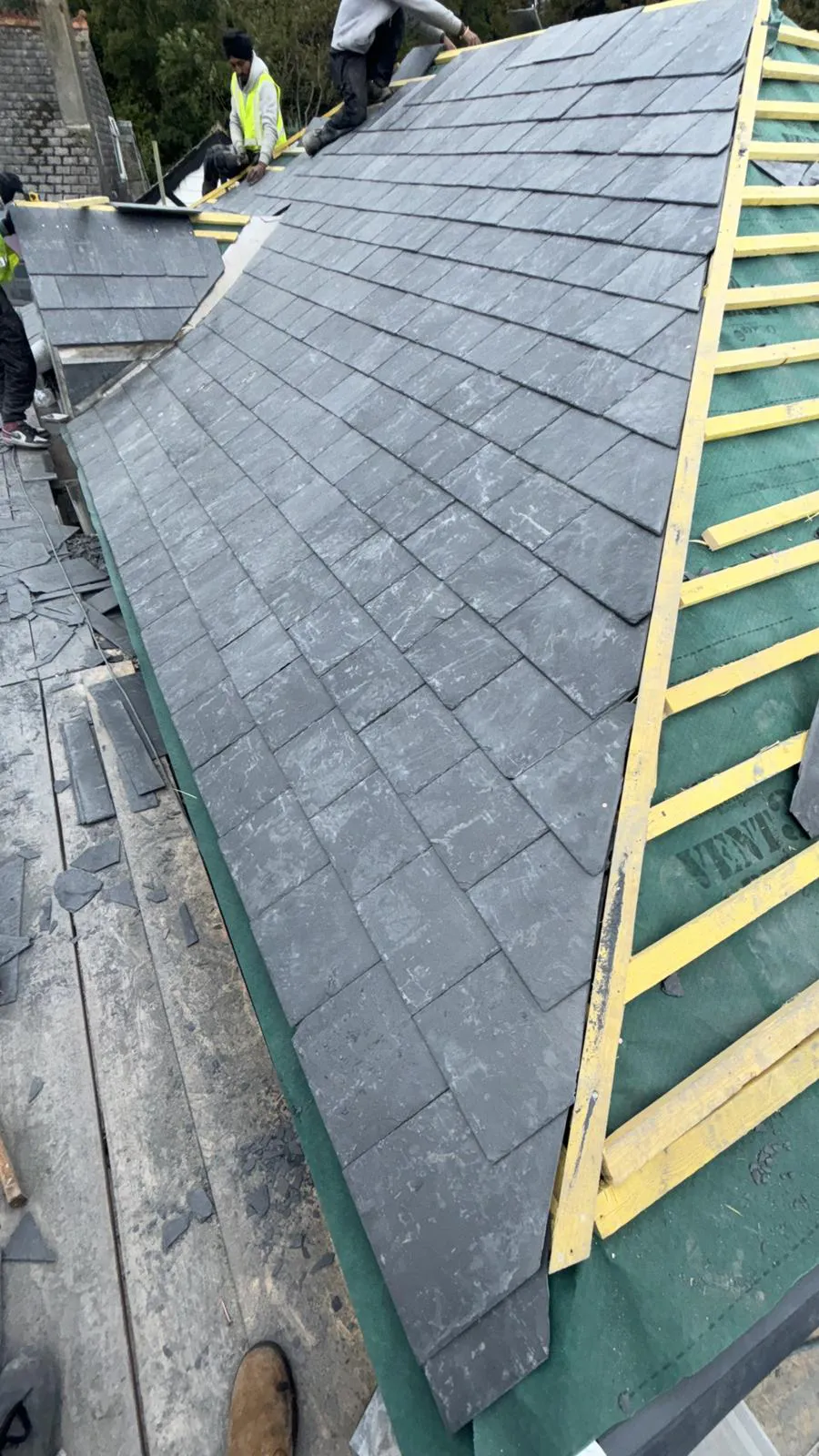 Natural slate roof installation in progress showing slate courses, breathable underlay, and treated timber battens