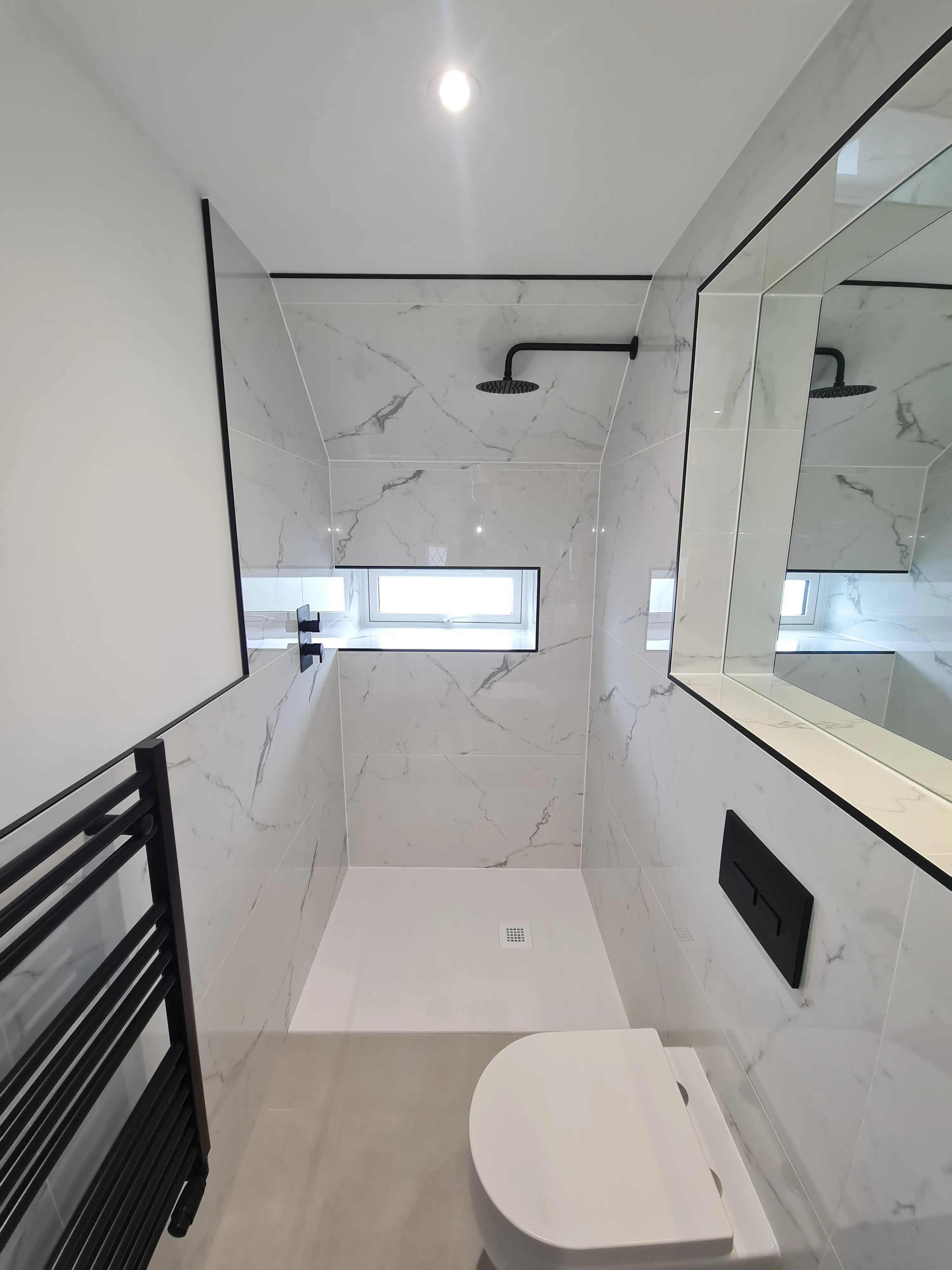 Luxury walk-in shower installation in Plymouth featuring marble tiles and black fixtures by Sands & Vossen.