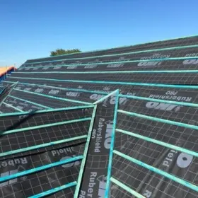 A close up of a pitched roof under construction, showing breathable felt and wooden battens ready for tiles or slates.