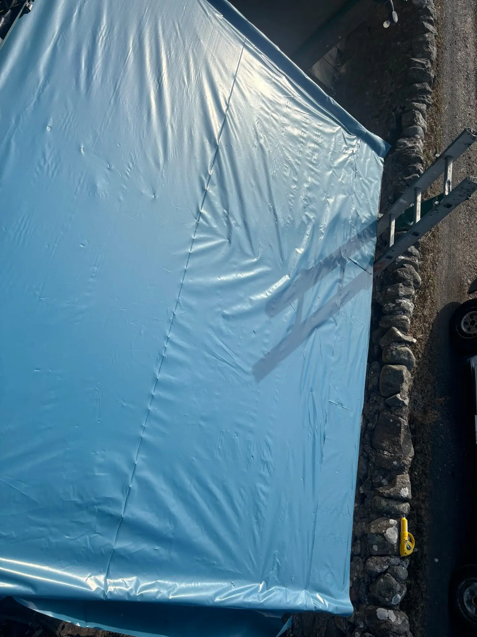 Blue tarpaulin installed as a temporary emergency roof covering to prevent leaks