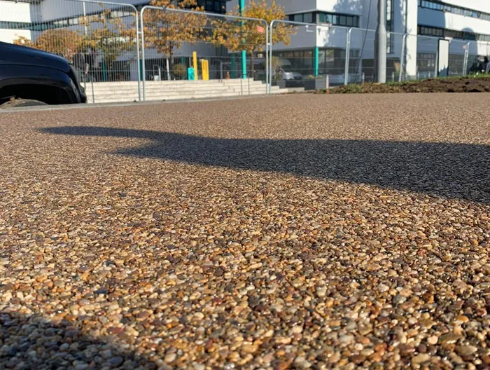 A close-up of a modern, permeable resin-bound driveway or pathway, featuring small, natural-coloured stones.