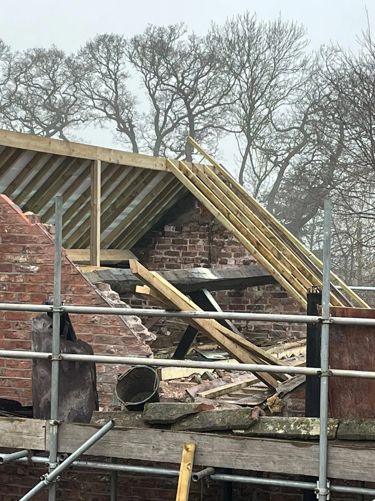New timber roof trusses being installed on a traditional brick building during a roof replacement or major repair project.