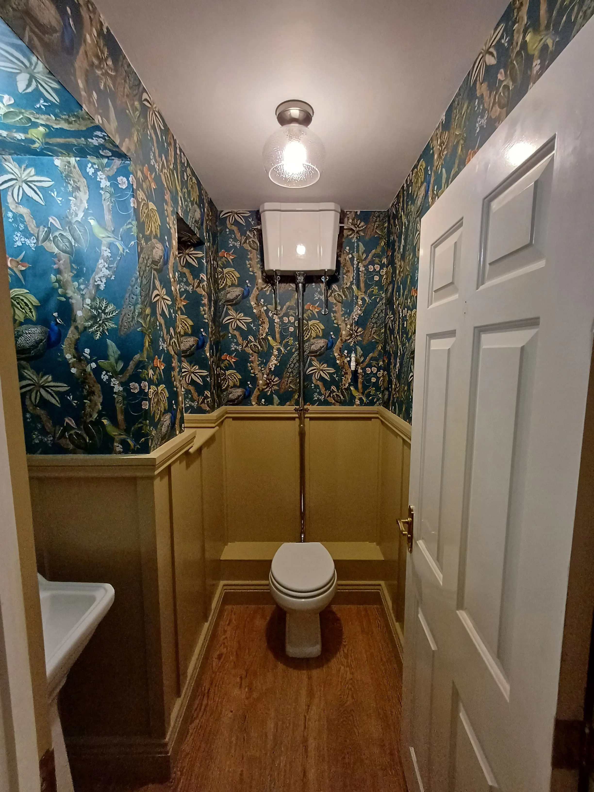 Luxury bespoke cloakroom design and installation in Plymouth featuring traditional high-level cistern and boutique wallpaper.