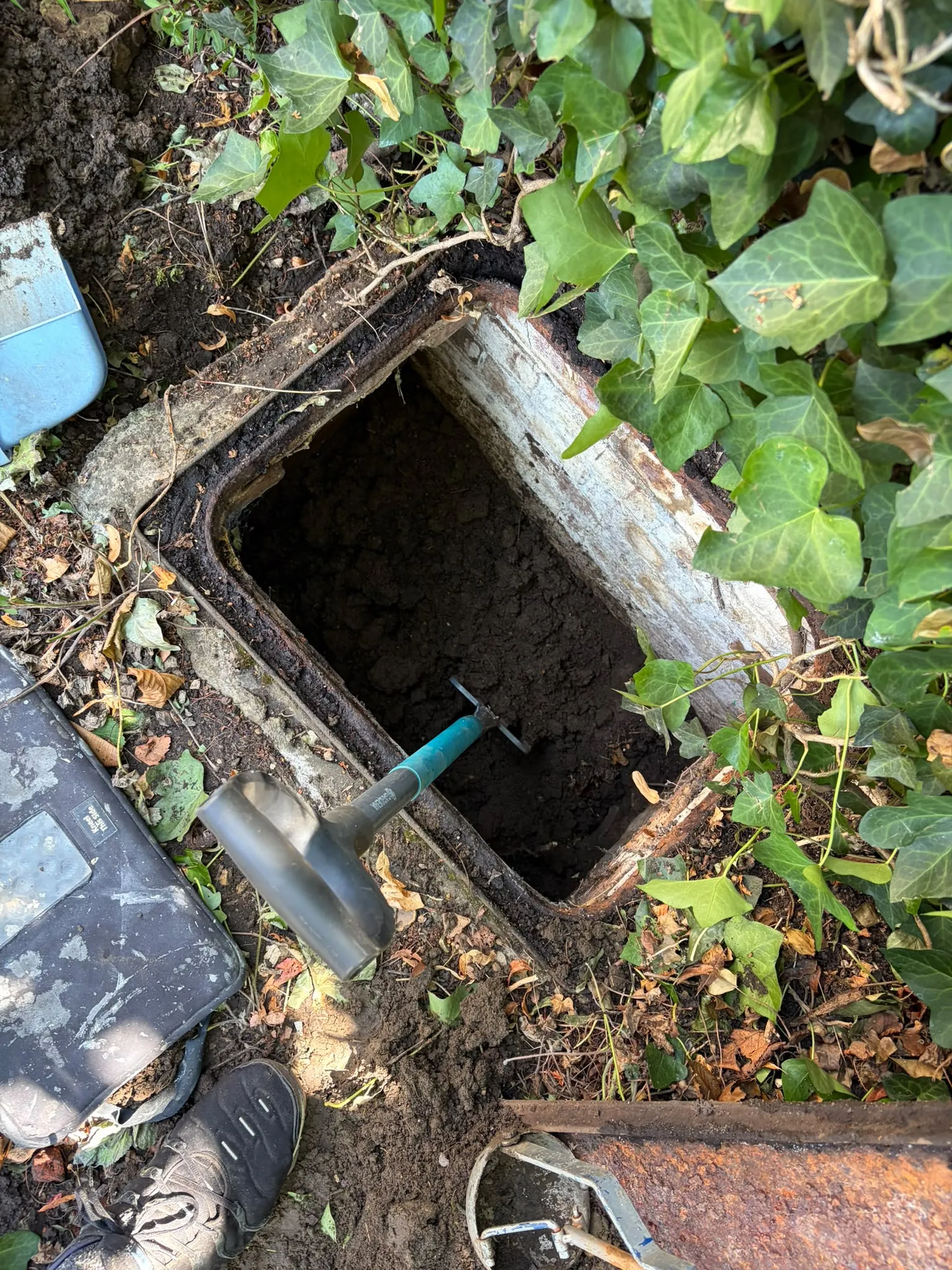 Inspection chamber being excavated and cleared of compacted earth and debris in Slough