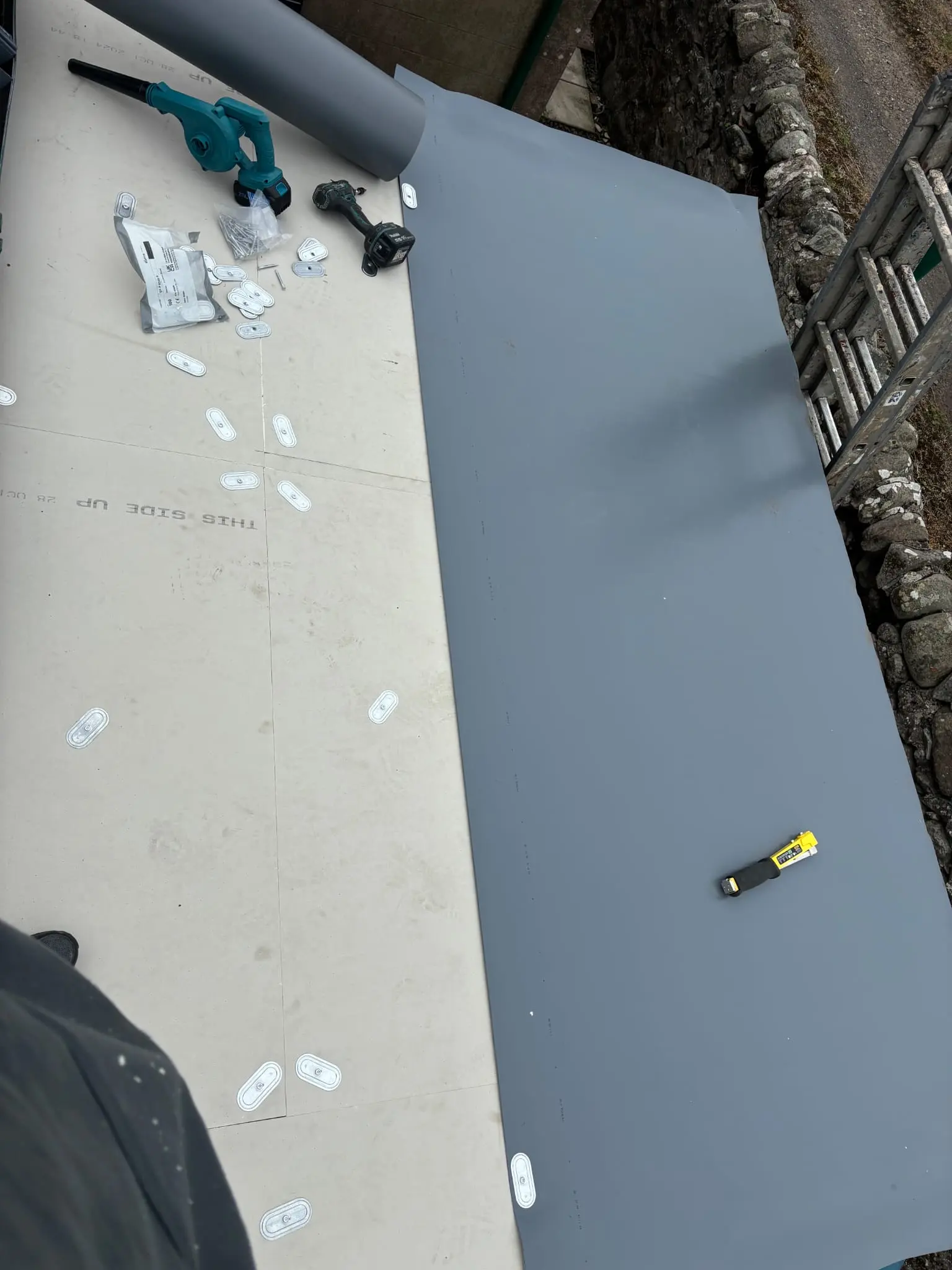 Flat roof installation in progress using a grey single-ply membrane.