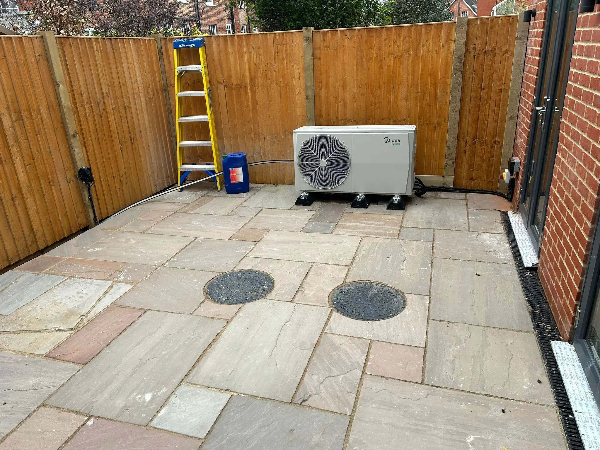 Newly installed sandstone patio with air source heat pump in a residential garden