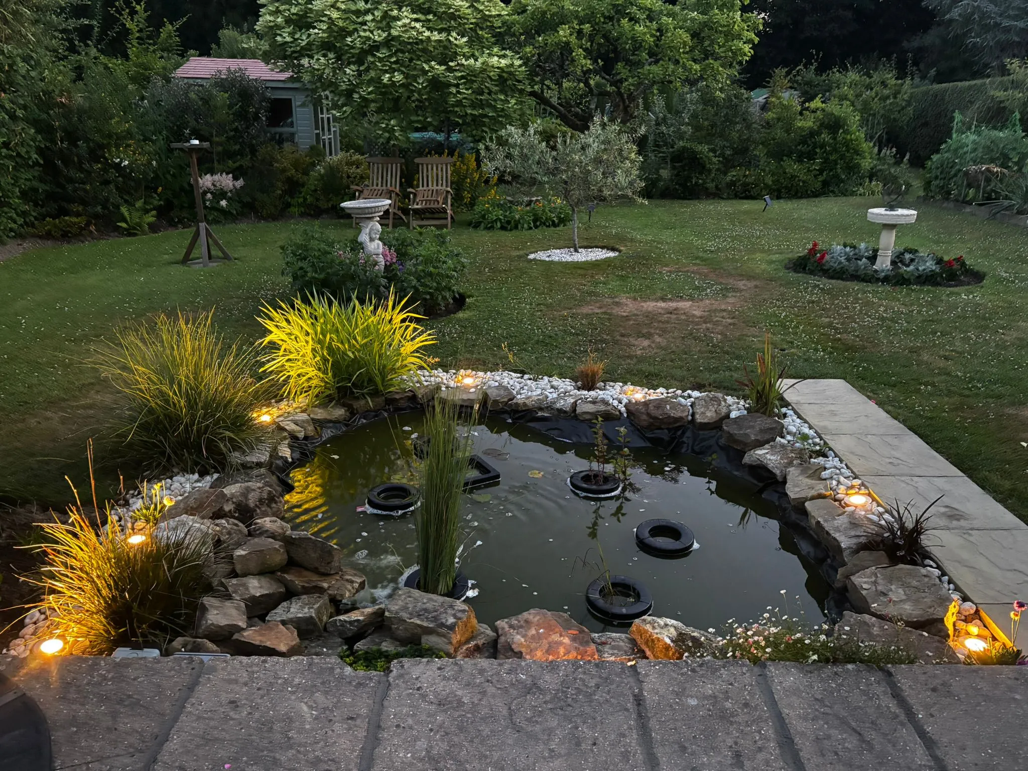 Outdoor garden pond lighting installation highlighting rockery and plants at dusk