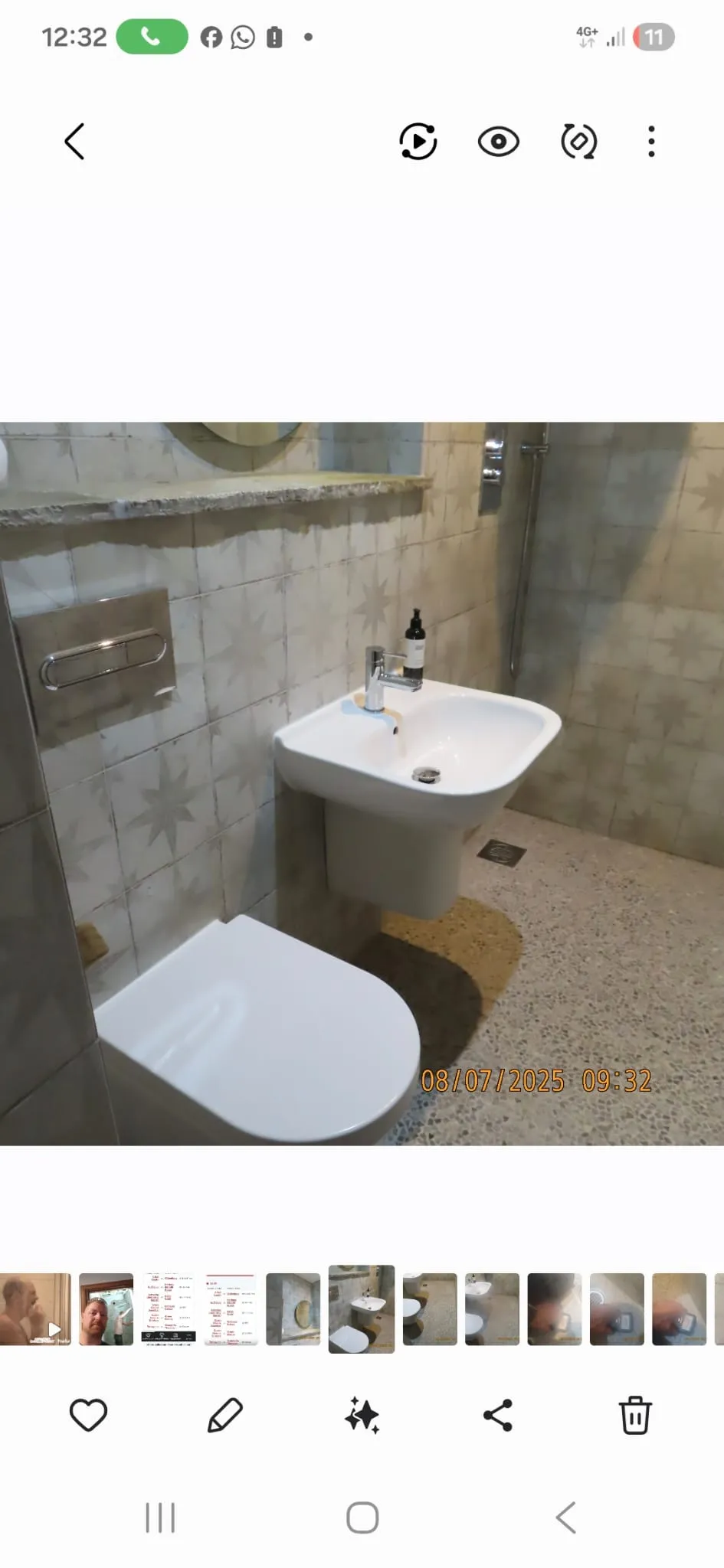 Modern bathroom refurbishment with a wall-mounted toilet, pedestal sink, tiled walls and floor, and a shower.