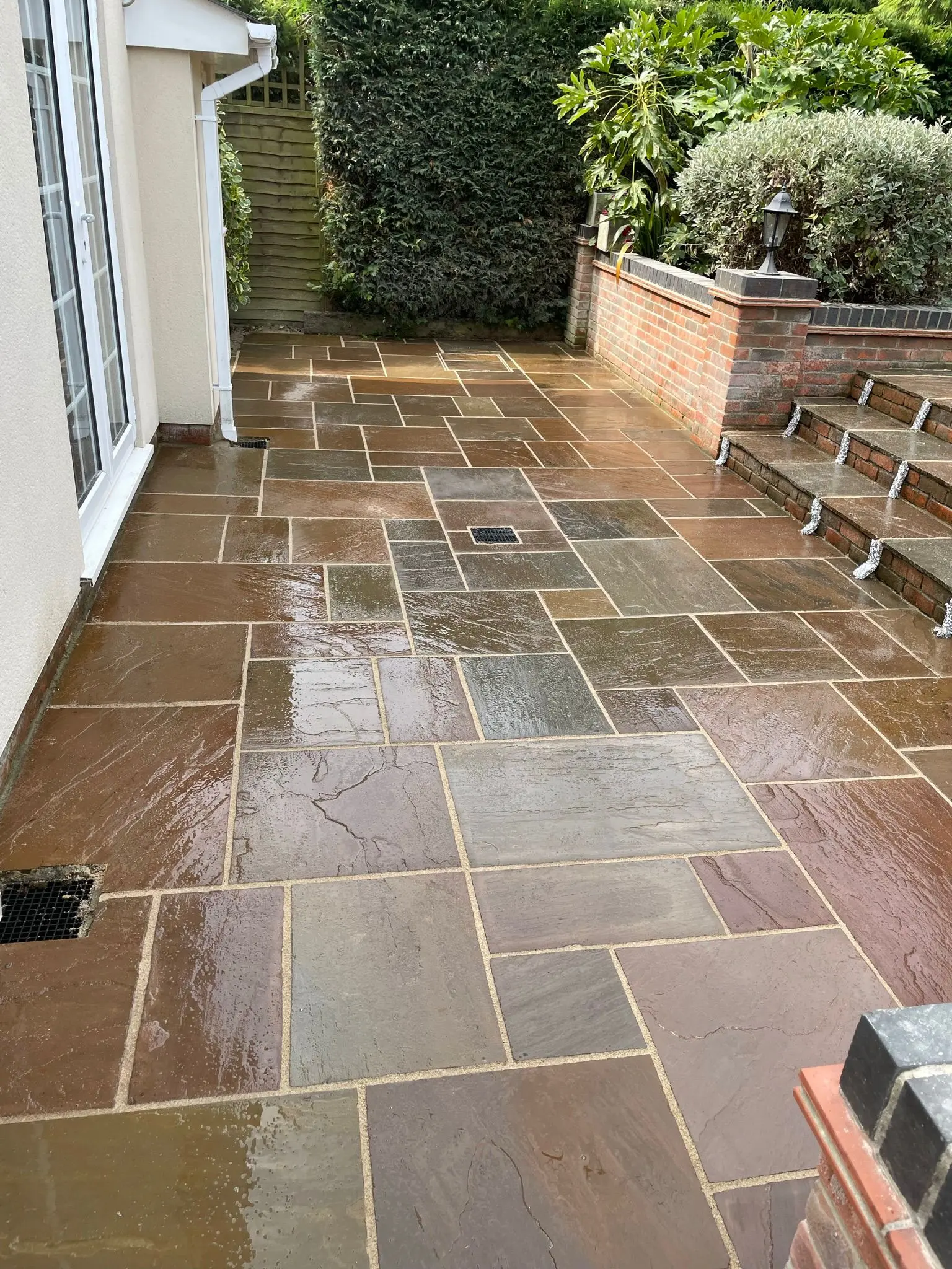 Freshly installed natural sandstone patio with brick steps by Aline Construction