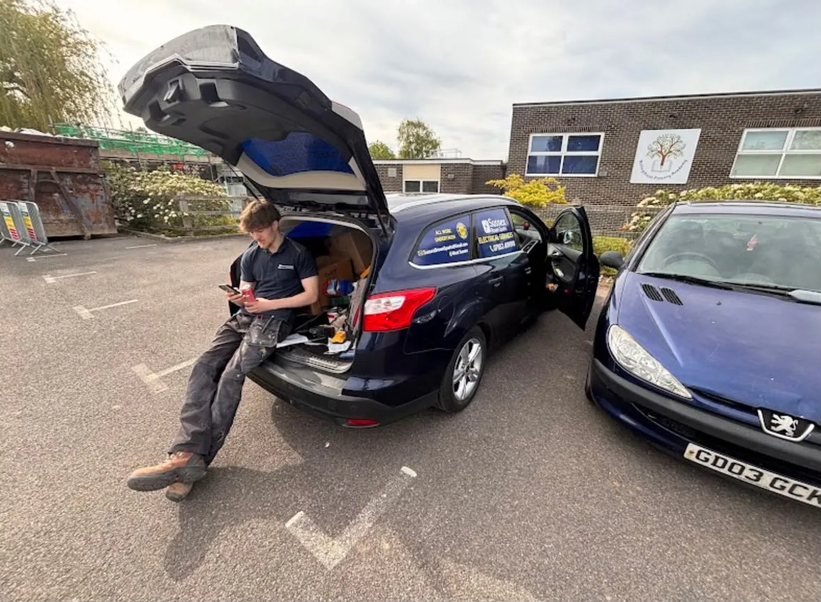 Sussex Brown Sparks electrician with company car outside a local commercial site