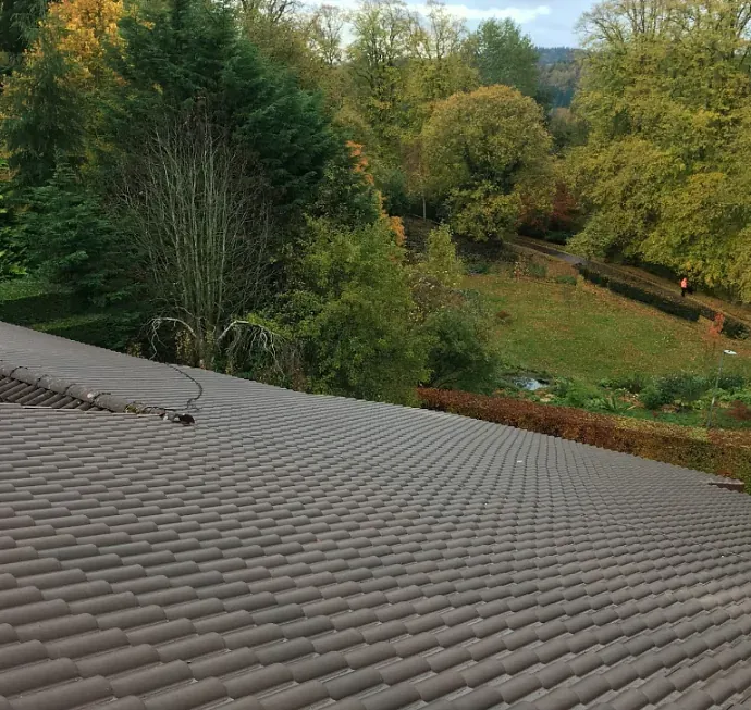 A modern concrete tile roof installation overlooking a landscaped garden.