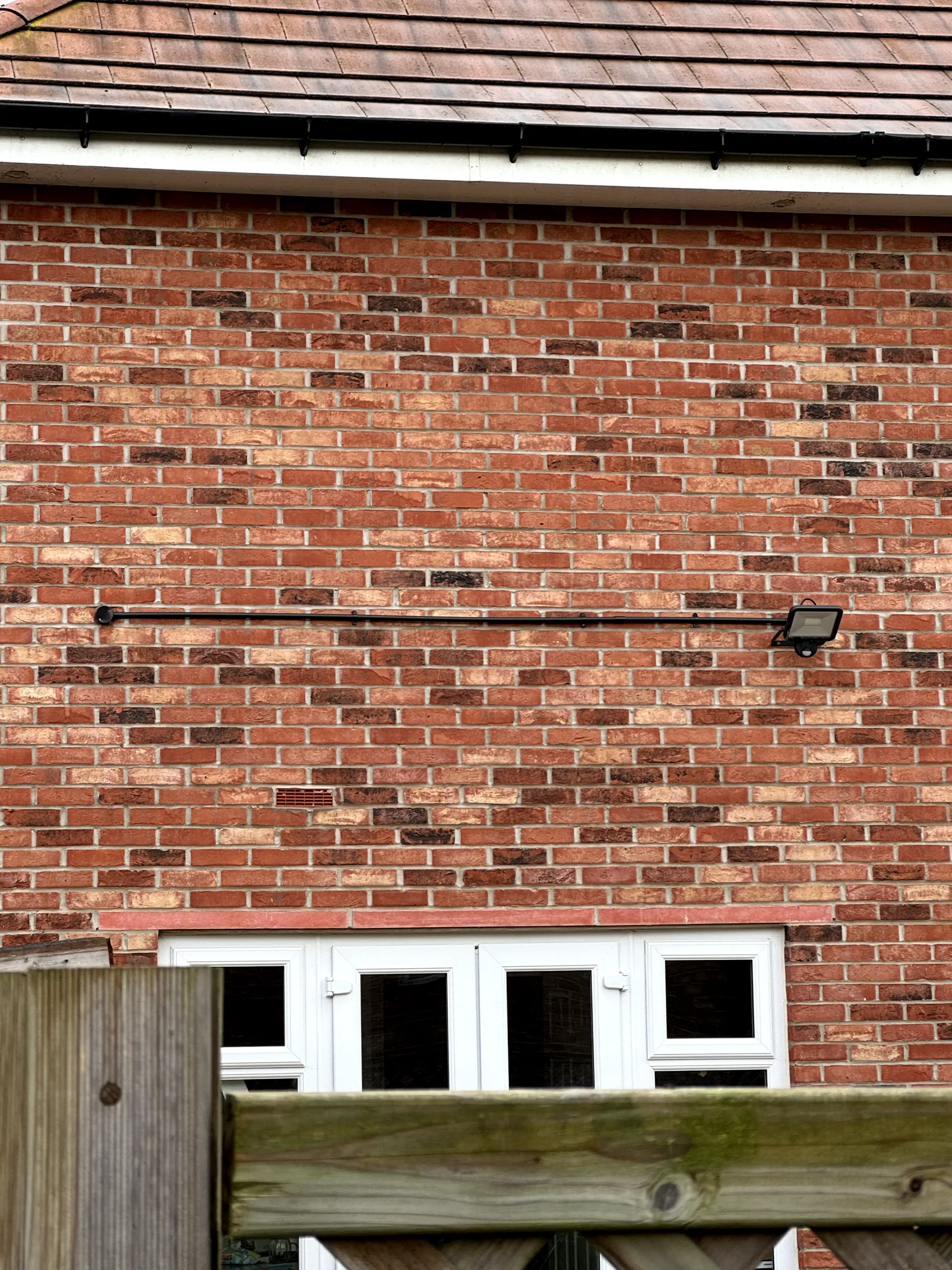 Professional external security light and conduit installation on a residential brick wall
