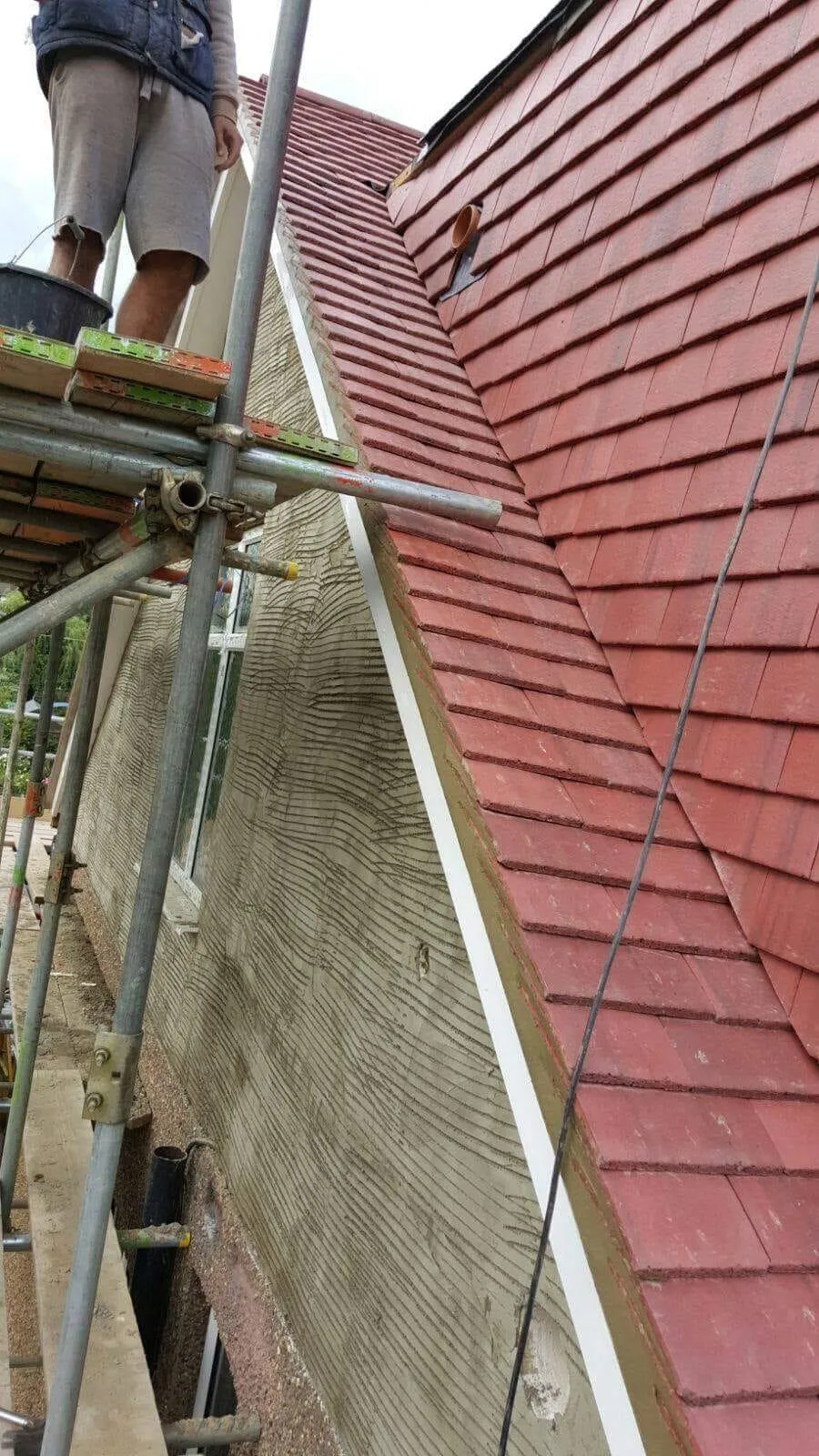 Expert roofer installing red roof tiles on a pitched roof in Buckinghamshire
