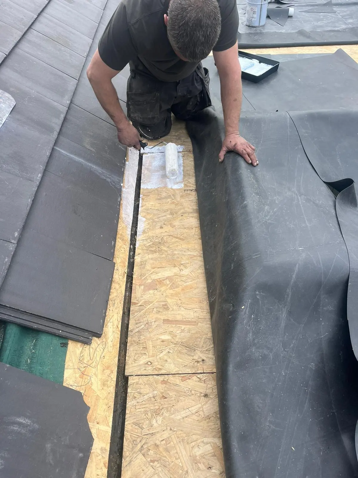 Roofer applying adhesive for an EPDM rubber flat roof installation