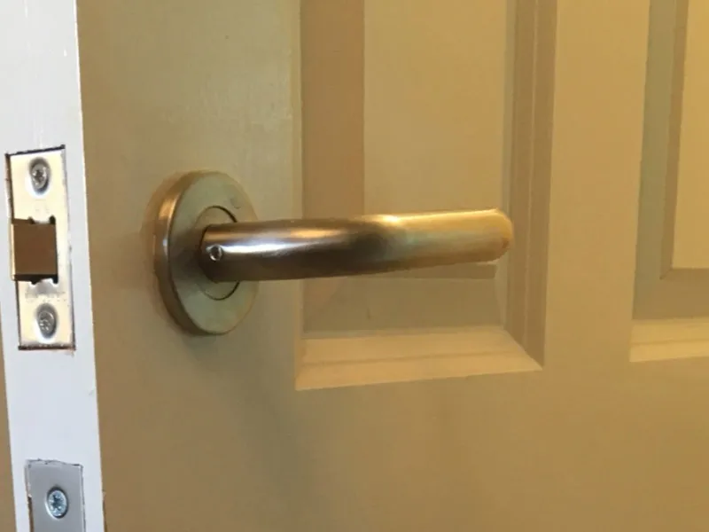 Lever-style door handle and latch on a wooden door