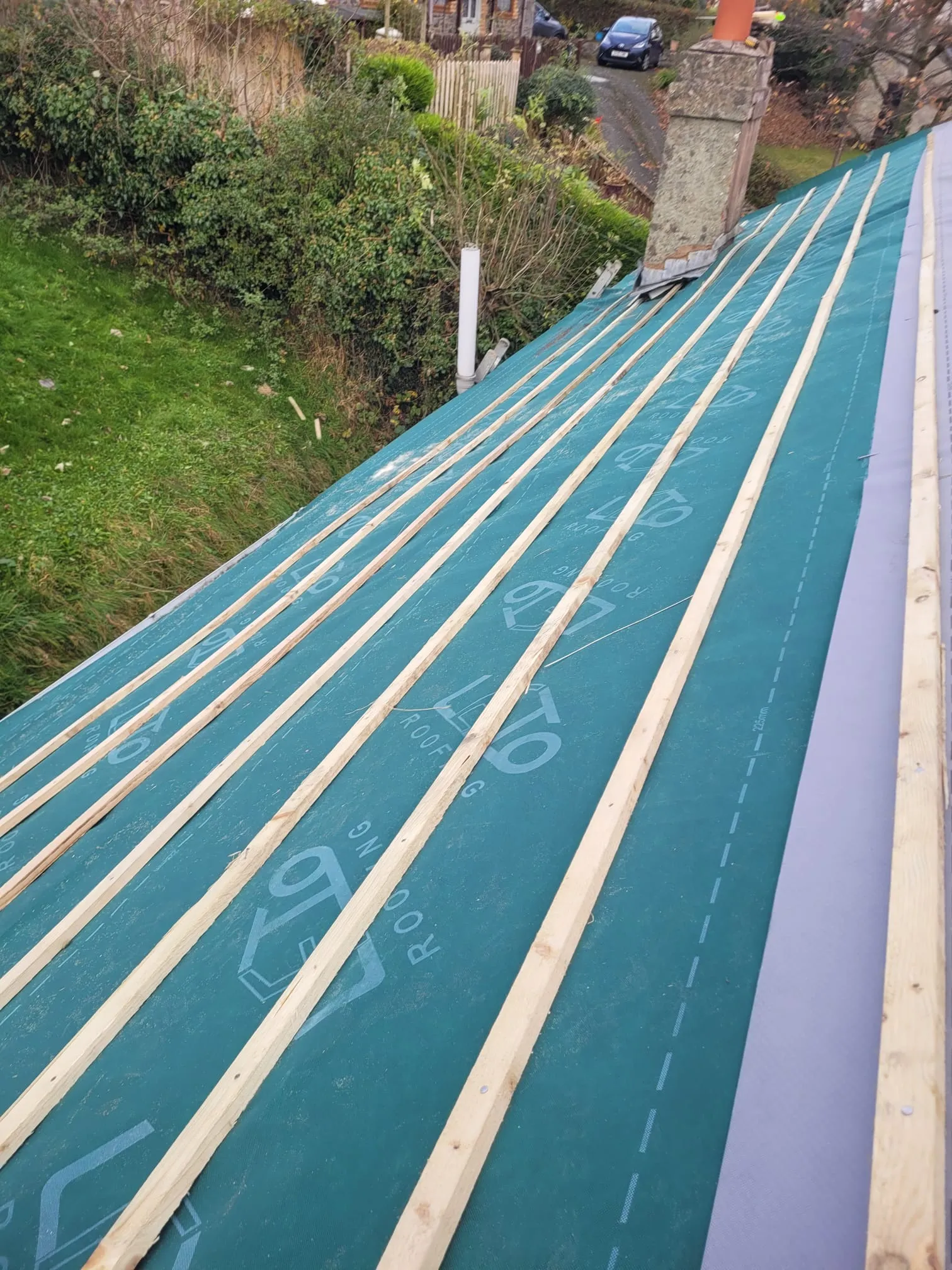 Newly installed breathable membrane and wooden battens on a pitched roof, part of a roof replacement project.