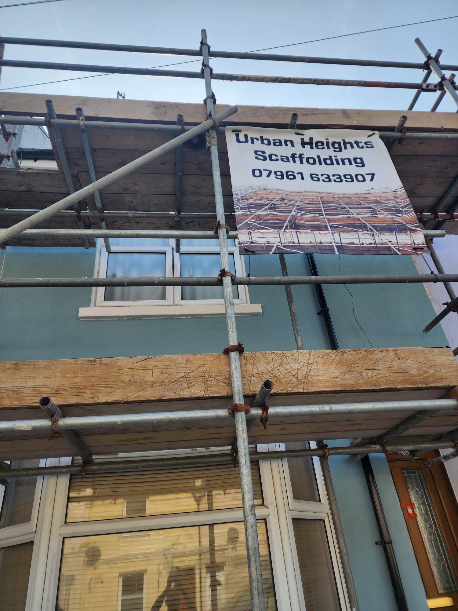 External rendering project in progress with scaffolding on a blue house