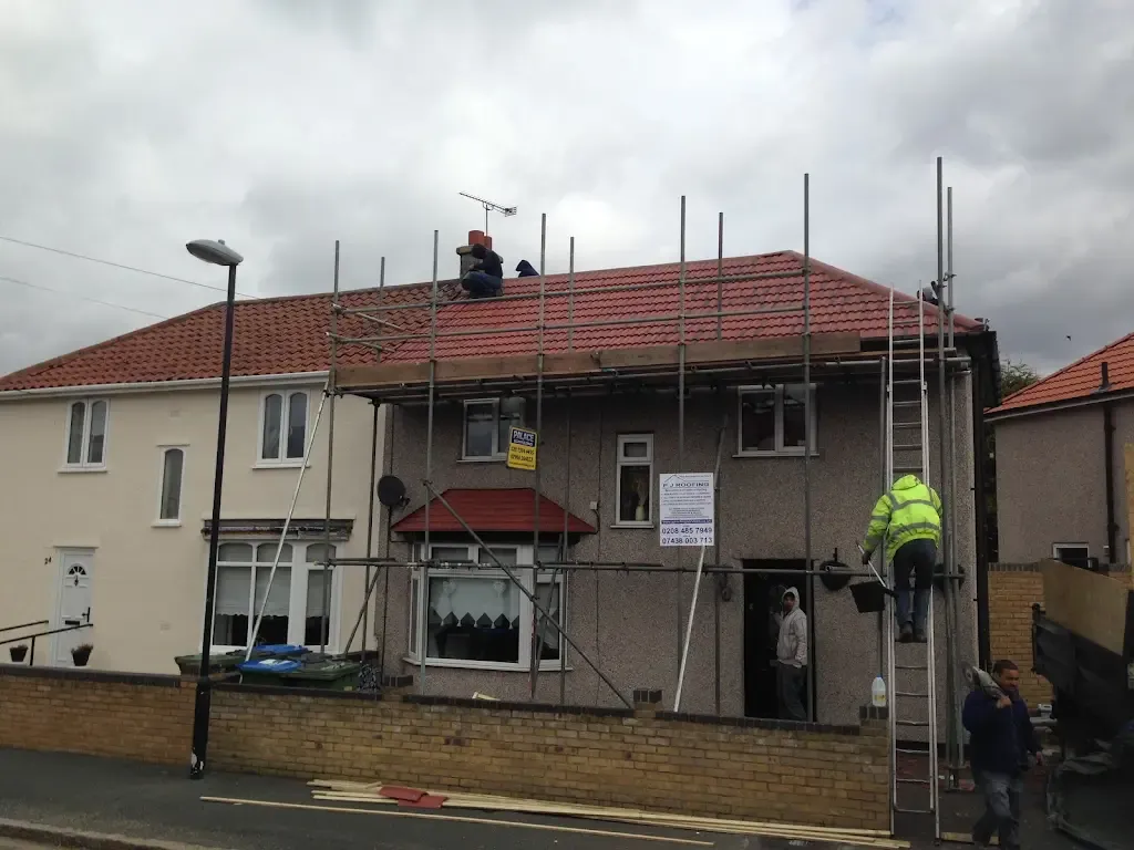 Roofers installing a new red-tiled roof on a residential property with full scaffolding, demonstrating a complete roof replacement service.