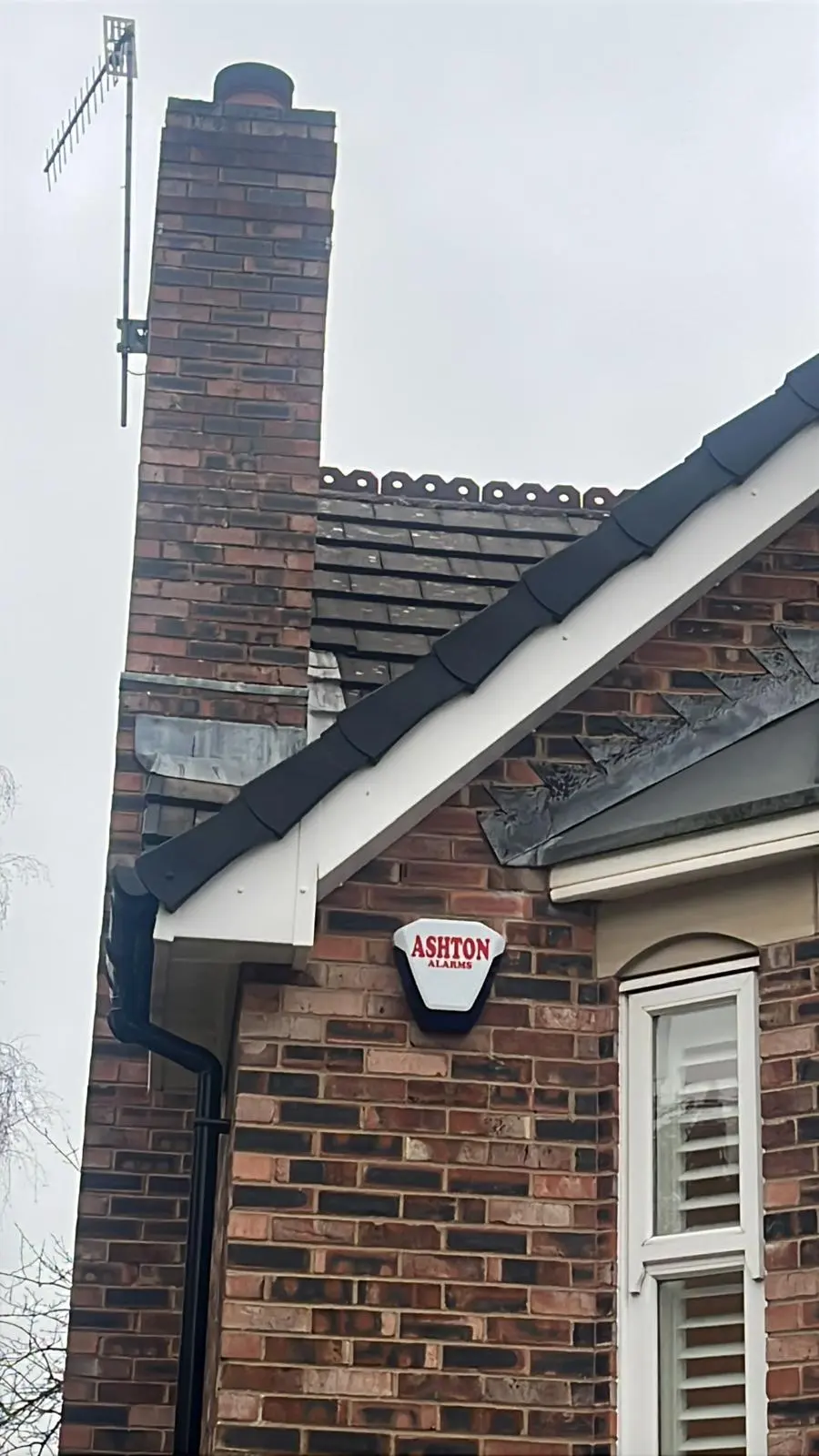 A brick chimney stack with lead flashing and newly installed uPVC fascias on a residential roofline