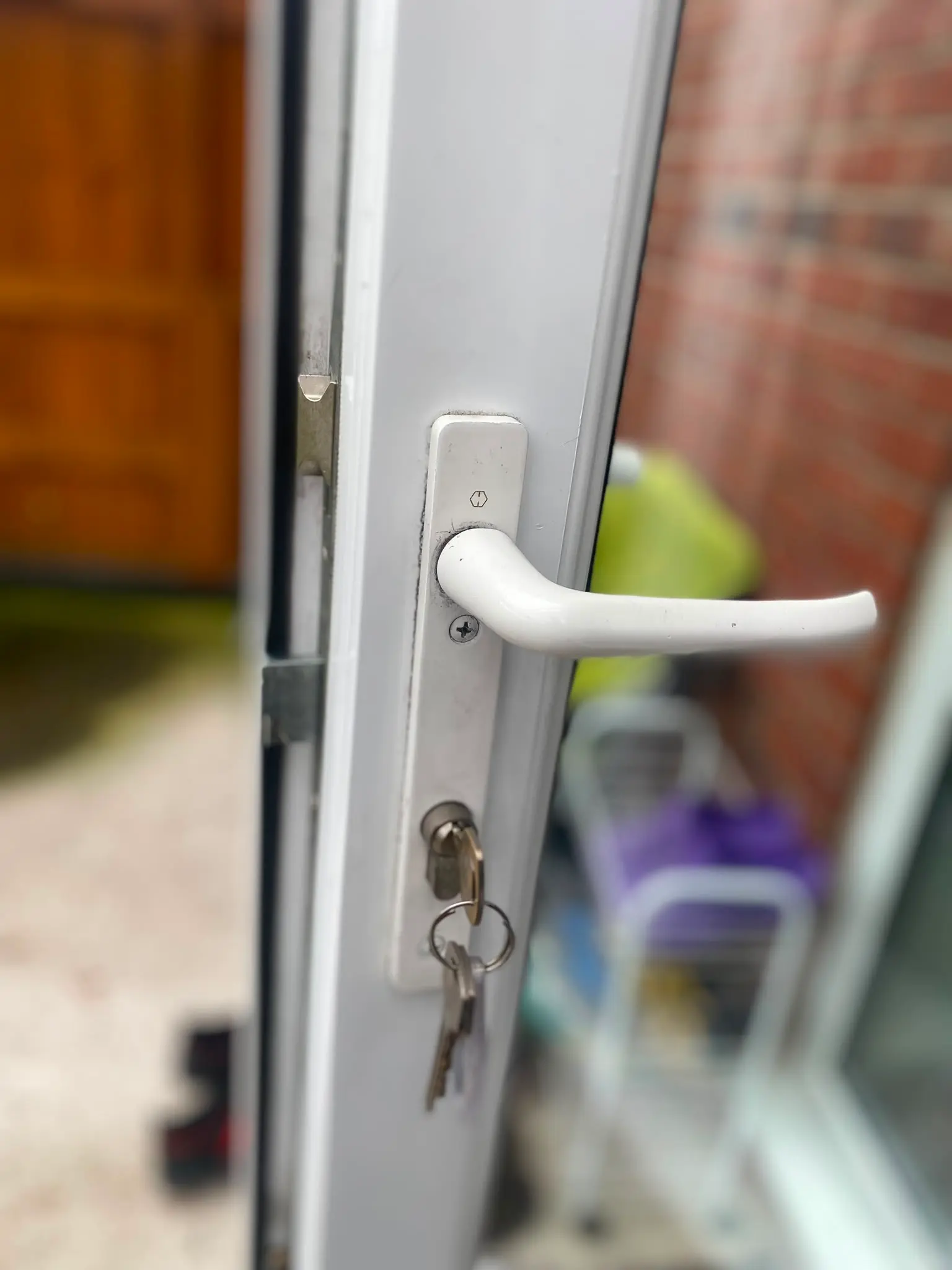 Close up of a white uPVC door handle and euro cylinder lock with keys hanging from the barrel
