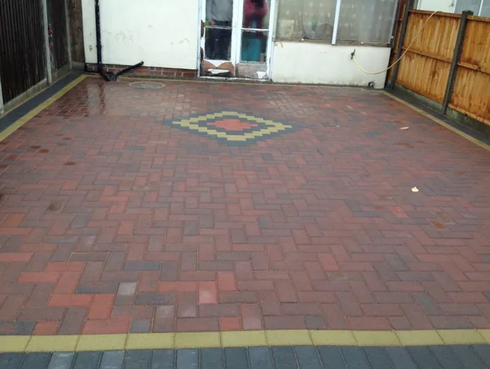 Finished block paving driveway with a red and black herringbone pattern and a decorative yellow and orange diamond in the centre.