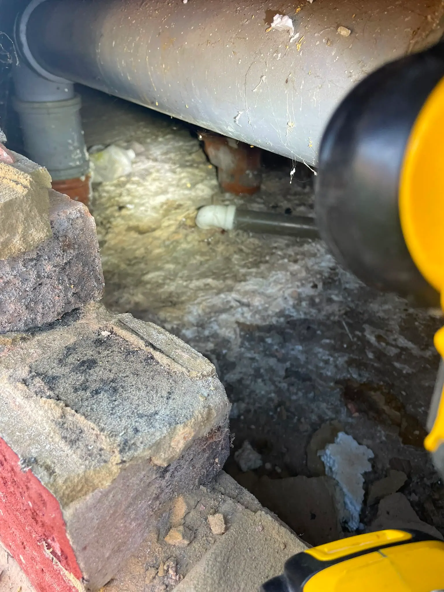 Plumber using a flashlight to inspect hidden pipework