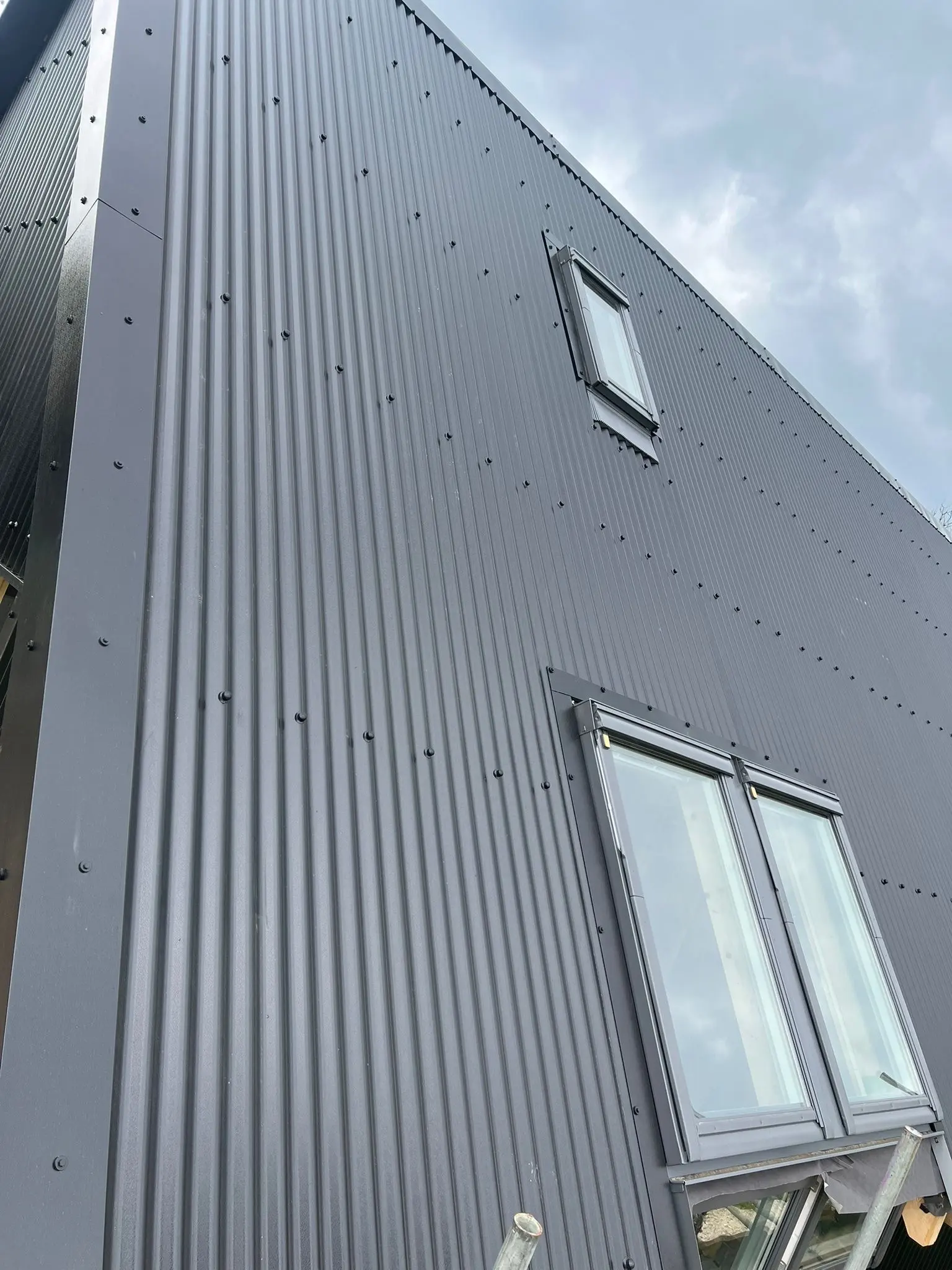 Dark grey weather-resistant corrugated metal cladding installed on a commercial building